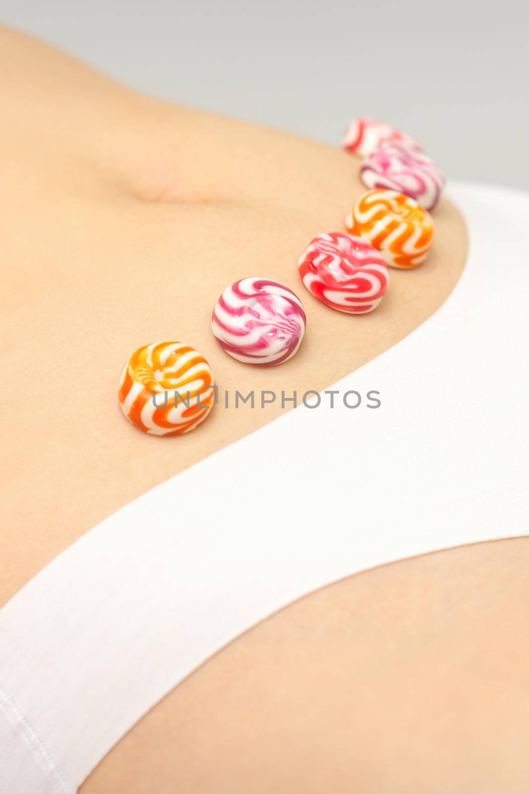 Concept of intimate depilation, intimate waxing, depilation. Round candies lying down in a row on the female bikini zone, intimate area, close up. by okskukuruza