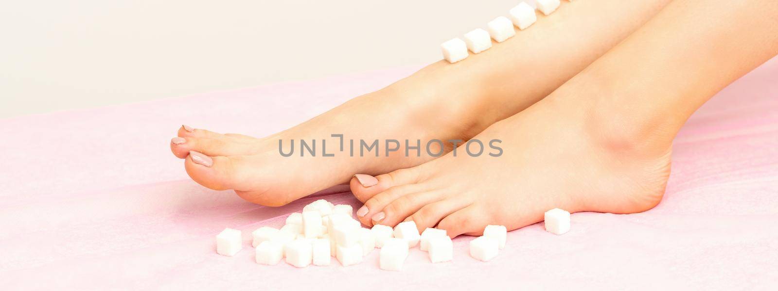 The concept of epilation, waxing. Sugar cubes lie down in a row on the naked white female leg