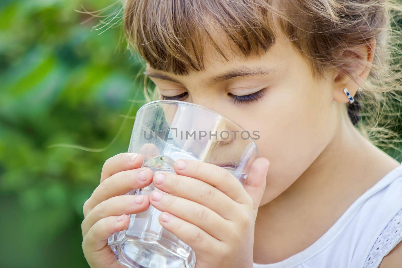 The child drinks clean water in summer. Selective focus. People.