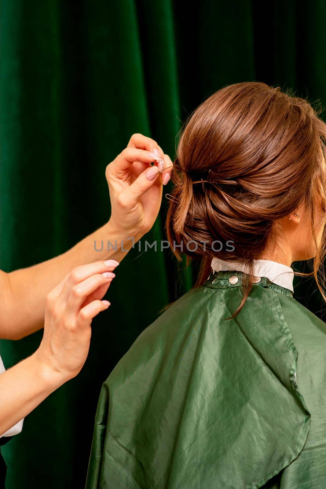 Hairstyling bride. A female hairdresser makes styling hair for the beautiful young caucasian woman in a beauty salon. by okskukuruza