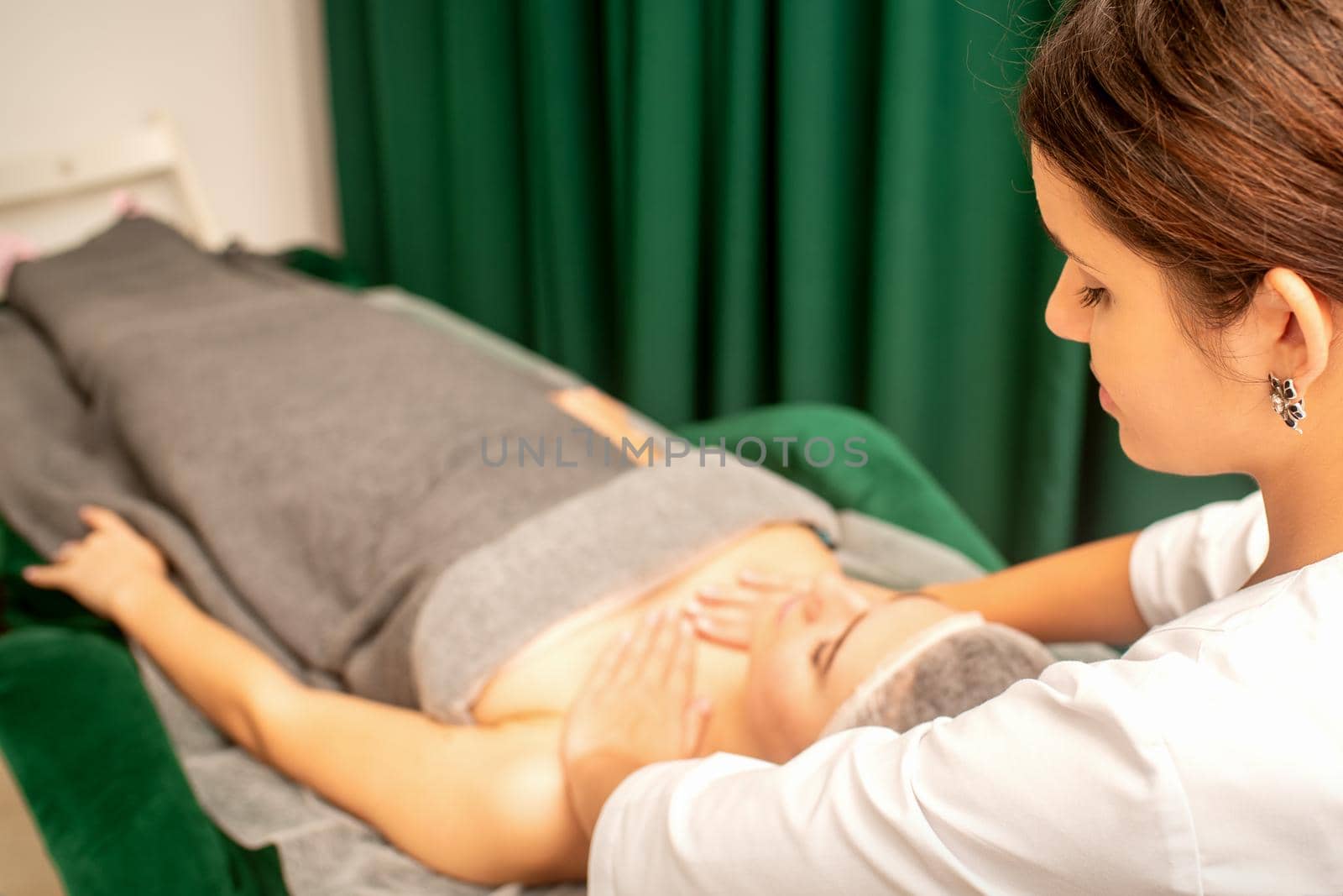 Massaging female breast, and shoulder. Beautician doing chest and shoulders massage of the young beautiful caucasian woman in beauty spa salon