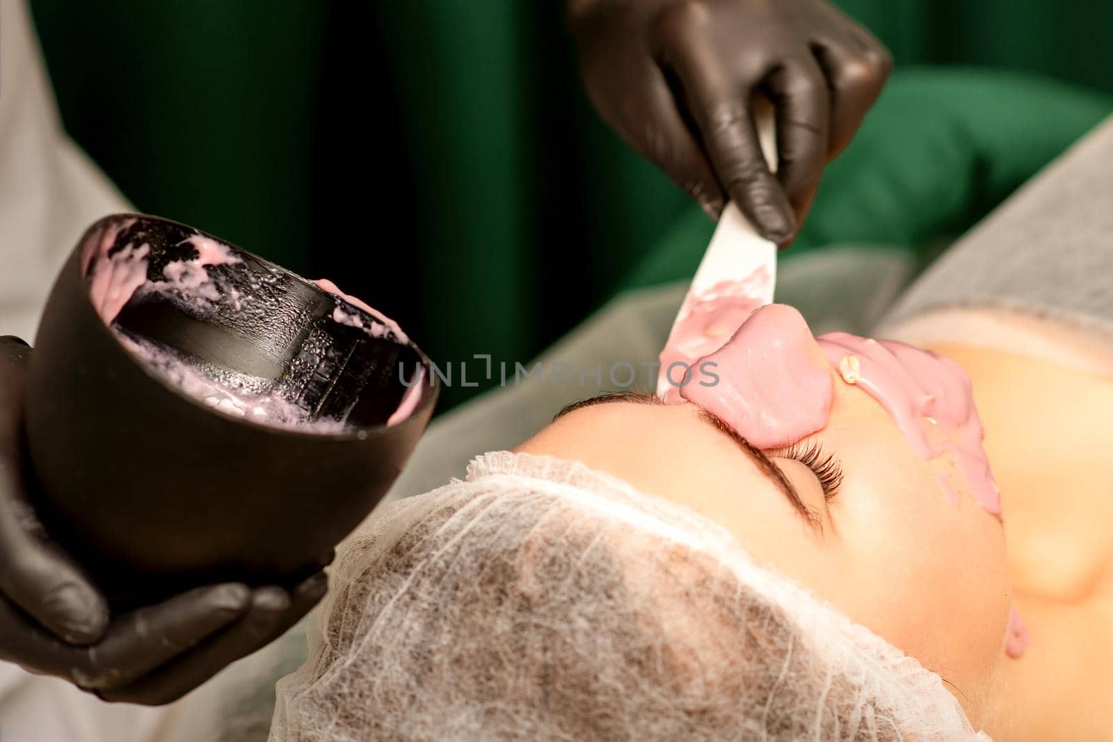 Beautiful young caucasian woman receiving an alginic mask to the face in beauty salon. Facial skin treatment