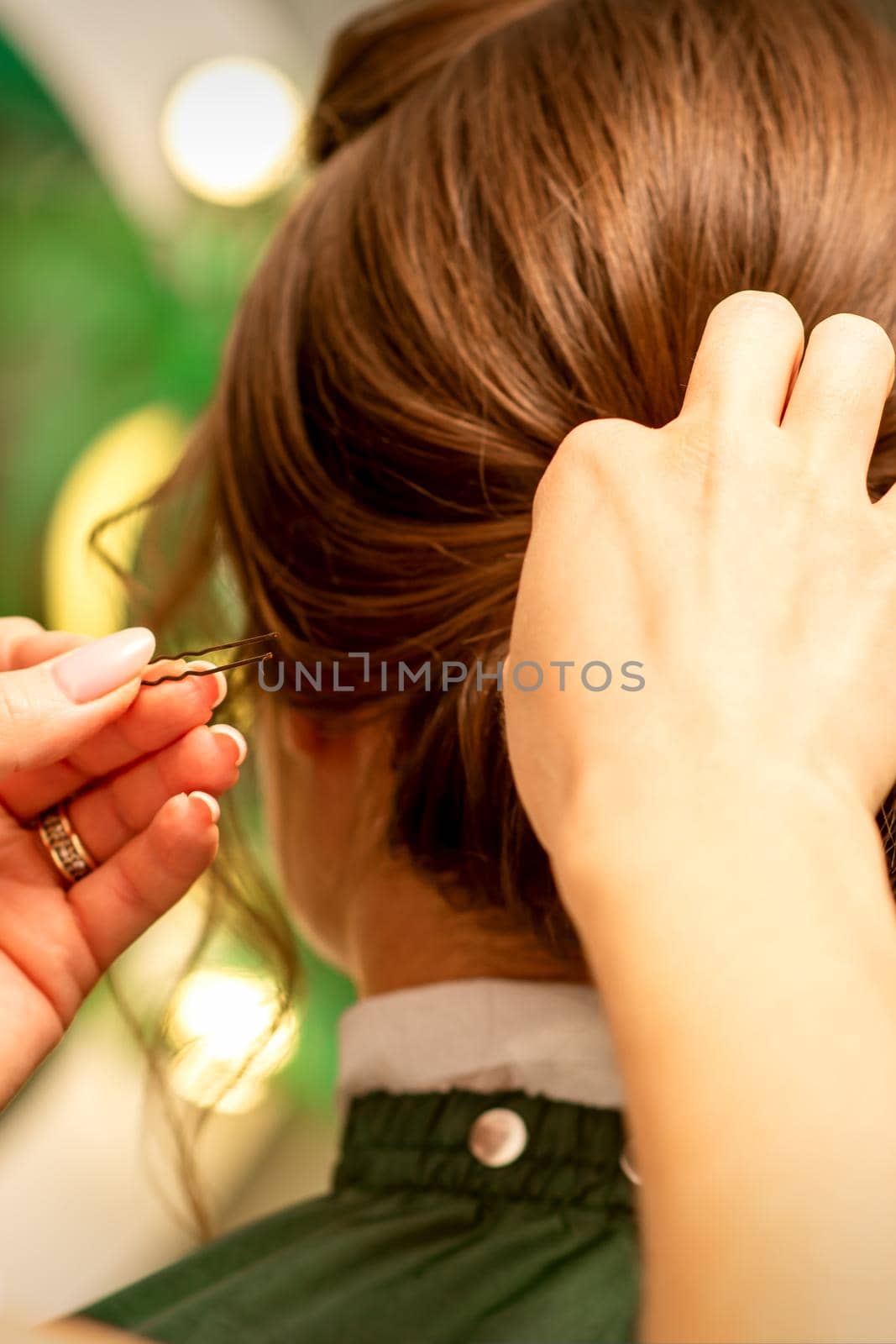 Hairstyling bride. A female hairdresser makes styling hair for the beautiful young caucasian woman in a beauty salon. by okskukuruza