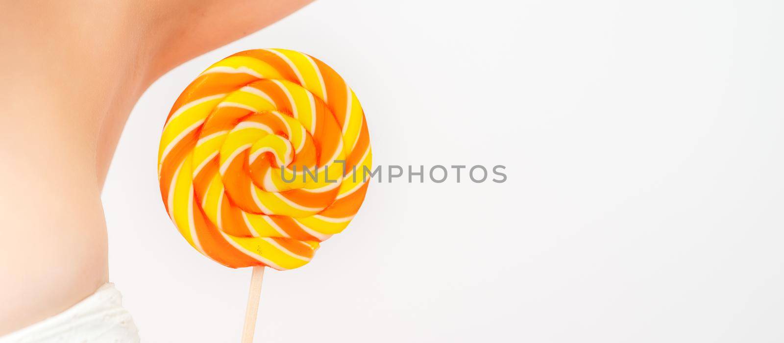 Waxing, depilation concept. A young female holds a round lollipop near her armpit on white background. by okskukuruza