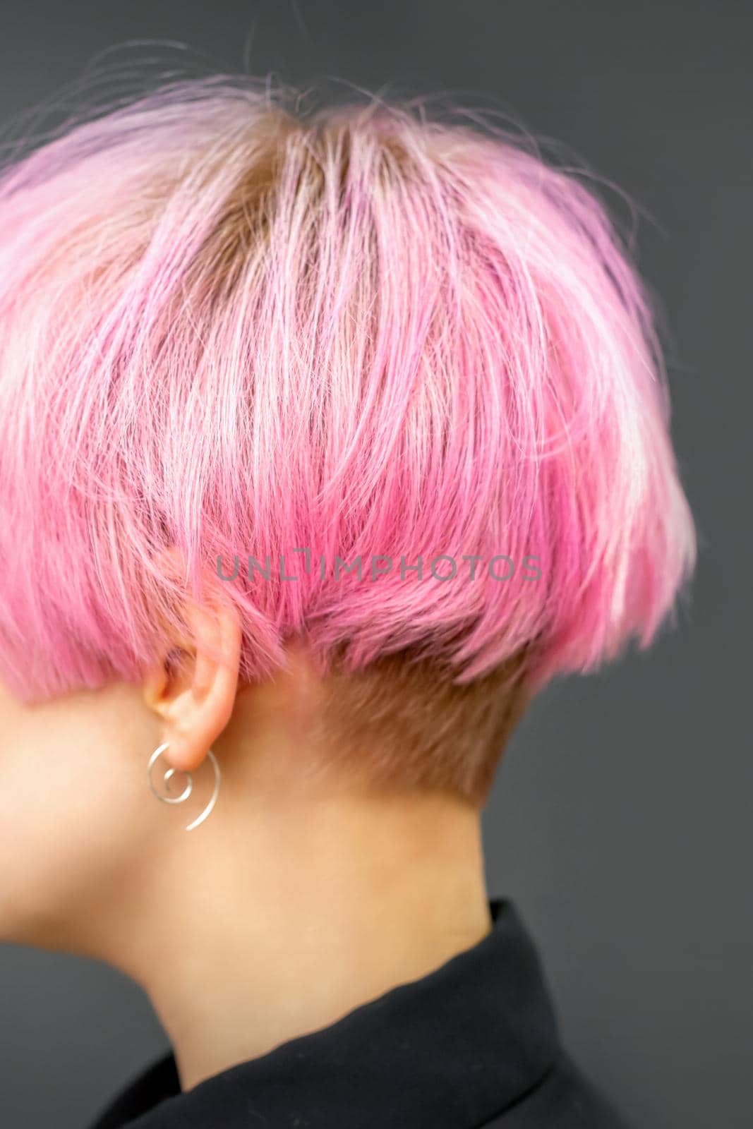 Profile of a beautiful young caucasian woman with short bob pink hairstyle on dark gray background. by okskukuruza