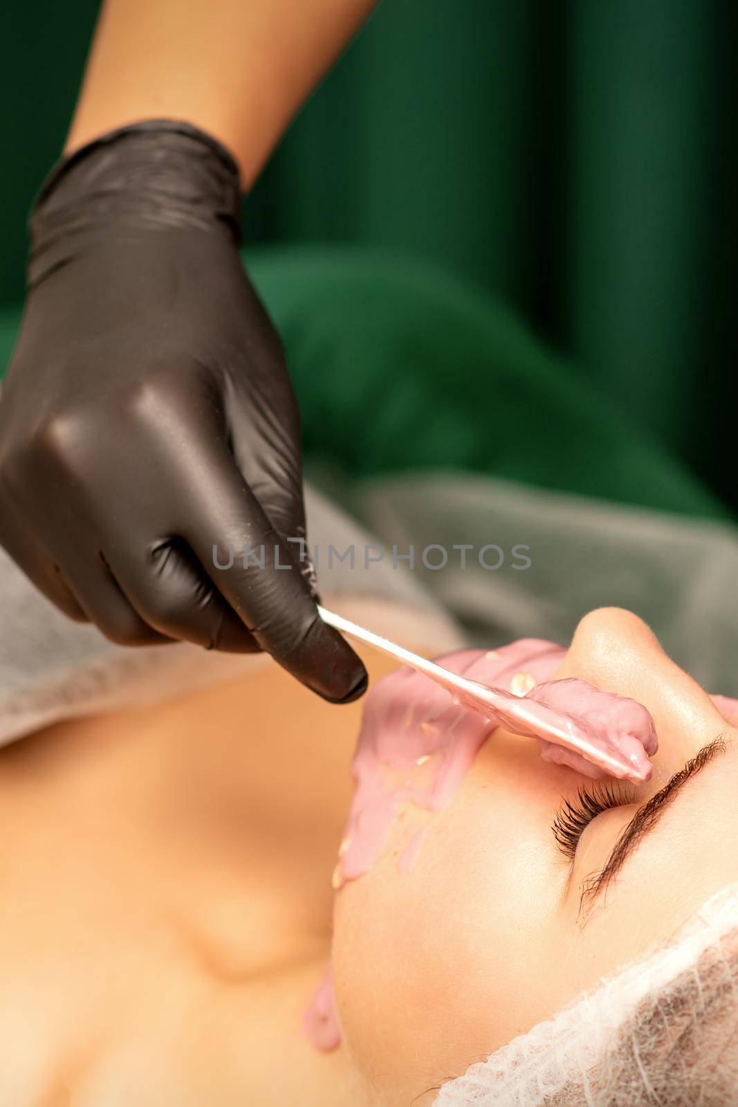 Beautiful young caucasian woman receiving an alginic mask to the face in beauty salon. Facial skin treatment