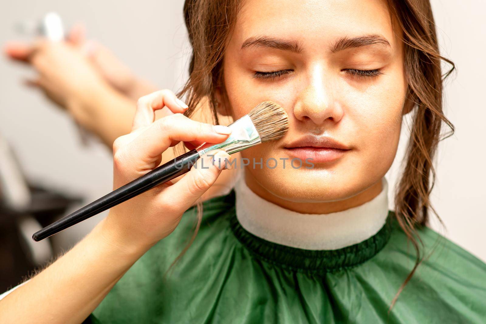 The makeup artist applies a cosmetic tonal foundation on the face using a makeup brush. by okskukuruza