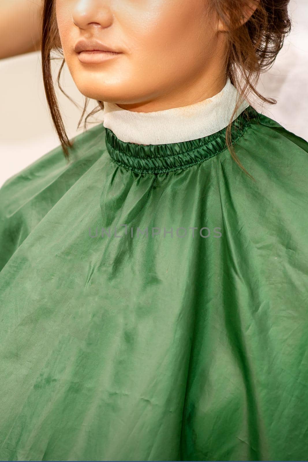 Beauty bride in a salon. Half face of the beautiful young caucasian woman wearing a green cape in a beauty salon. by okskukuruza