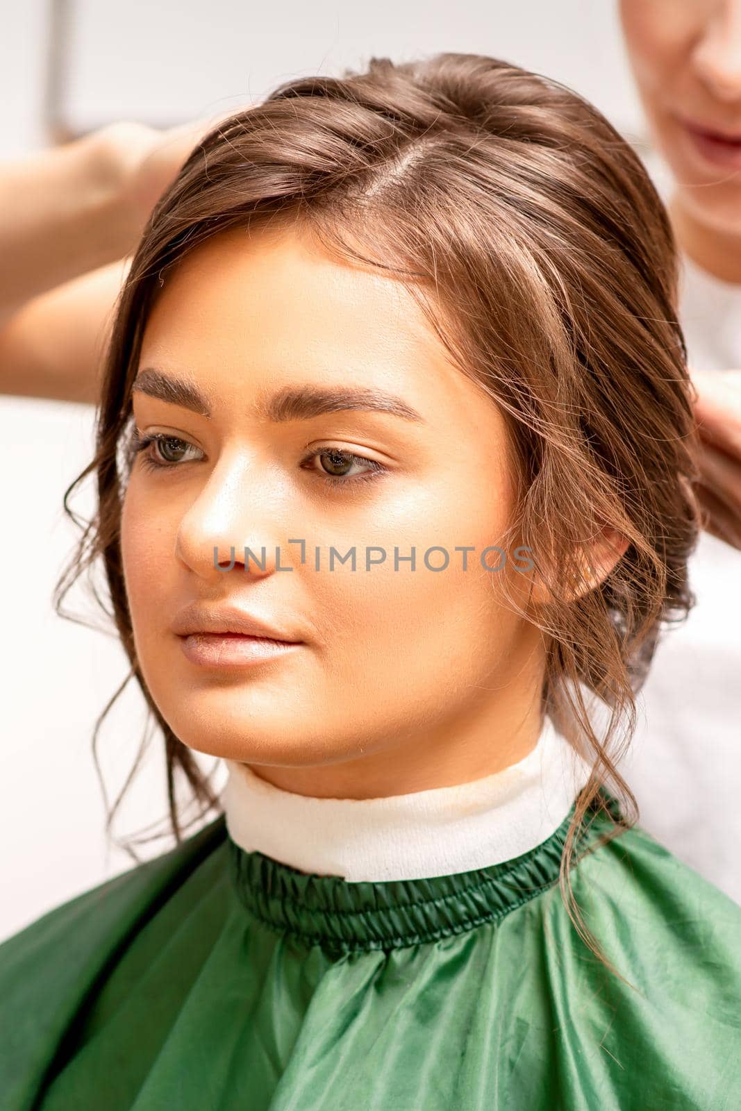 Hairstyling bride. A female hairdresser makes styling hair for the beautiful young caucasian woman in a beauty salon