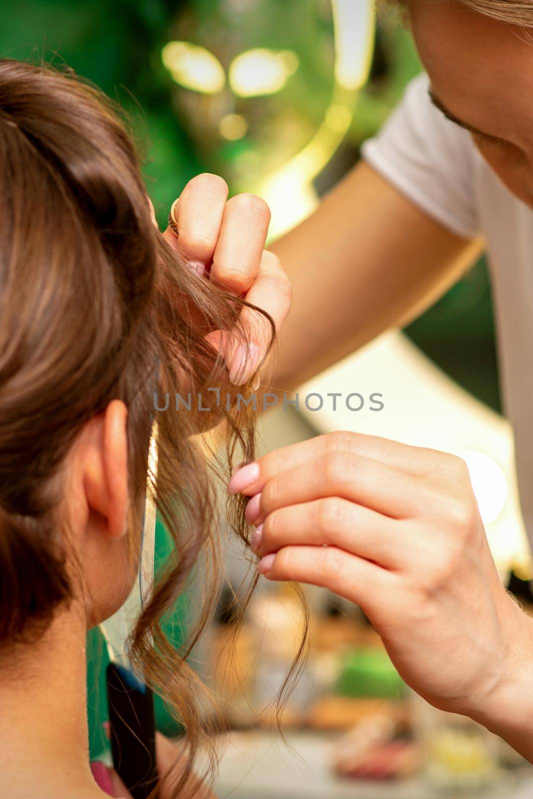 Hairstyling bride. A female hairdresser makes styling hair for the beautiful young caucasian woman in a beauty salon. by okskukuruza