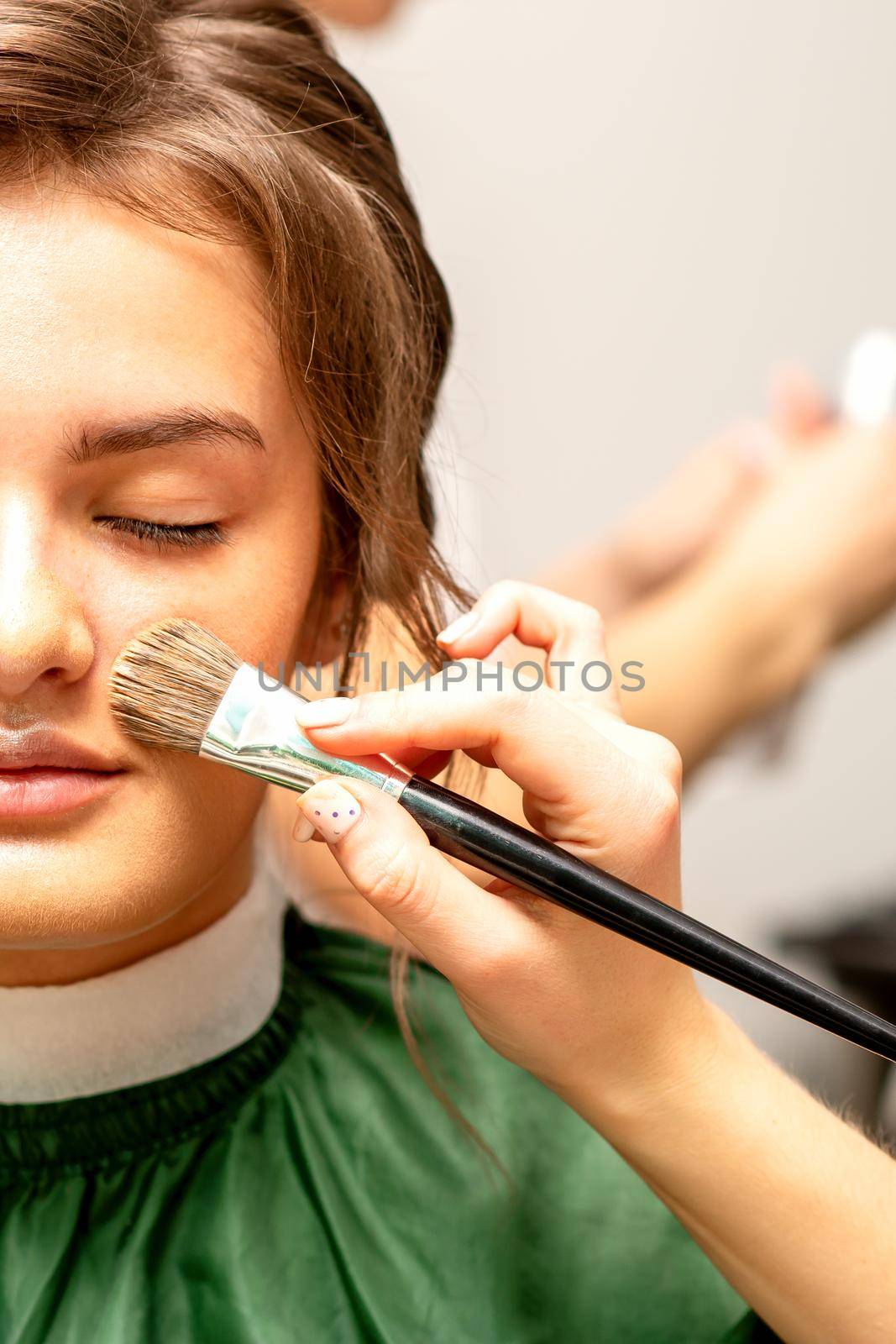 The makeup artist applies a cosmetic tonal foundation on the face using a makeup brush. by okskukuruza