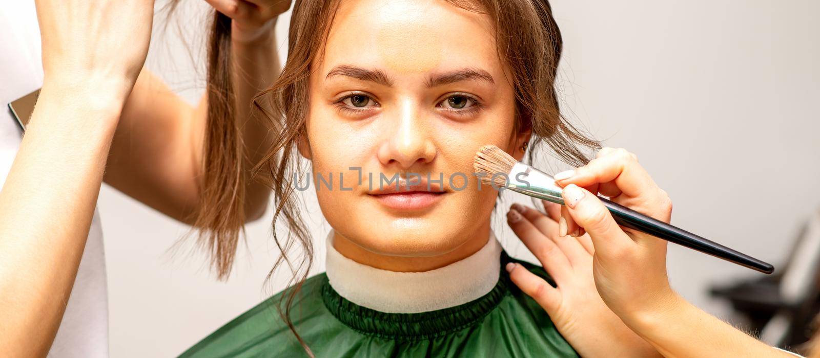 Makeup artist and hairdresser prepare the bride making hairstyle and makeup in a beauty salon. by okskukuruza