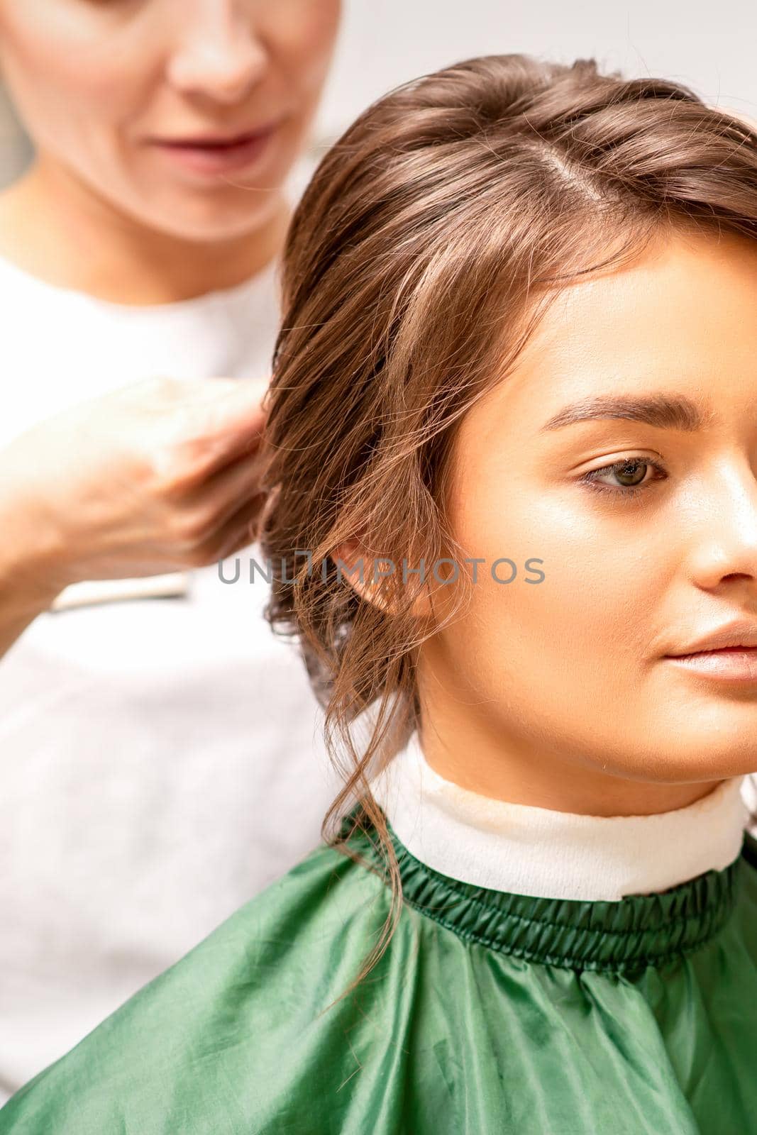 Hairstyling bride. A female hairdresser makes styling hair for the beautiful young caucasian woman in a beauty salon