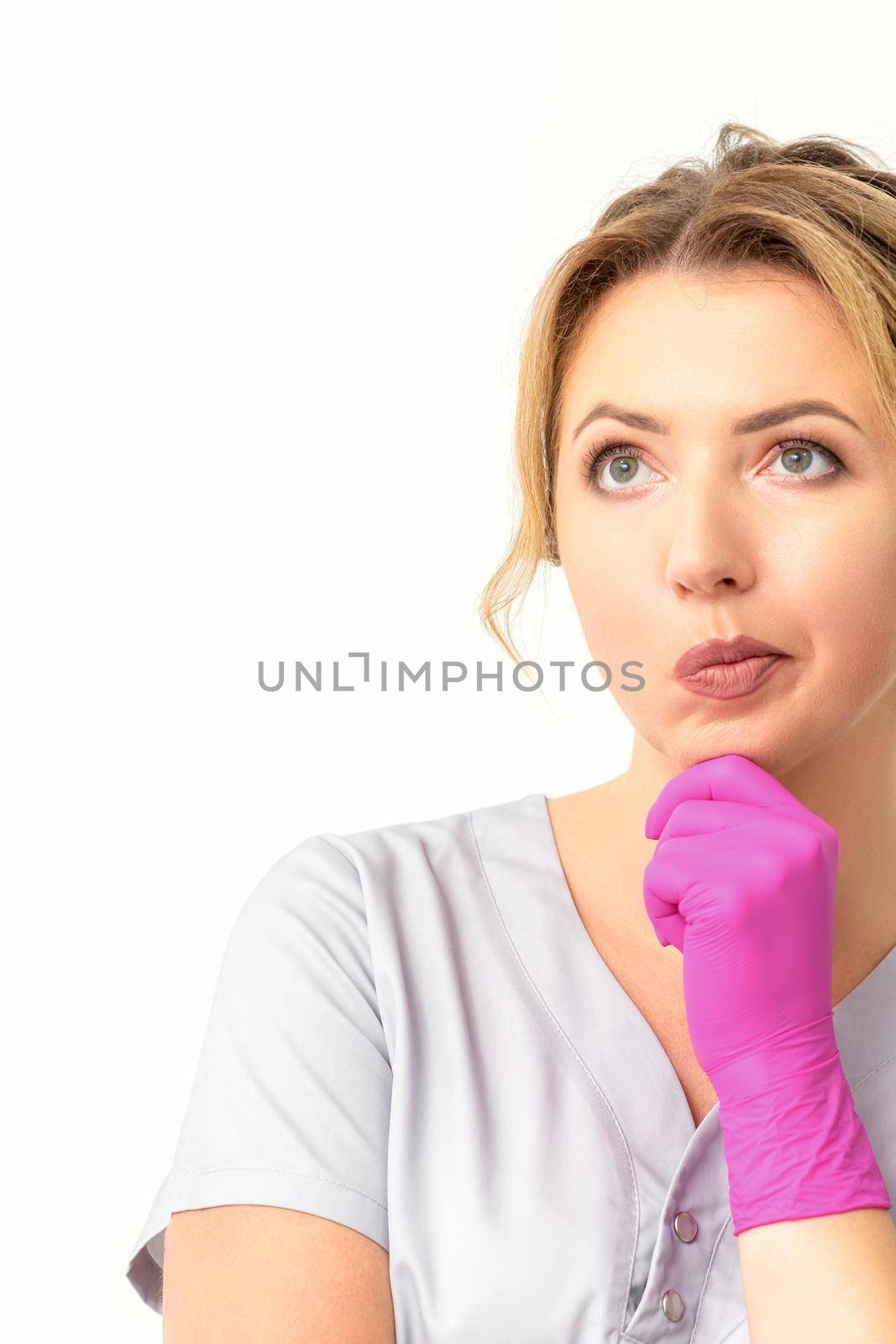 Young caucasian female doctor wearing gloves thoughtful looking away isolated on white background