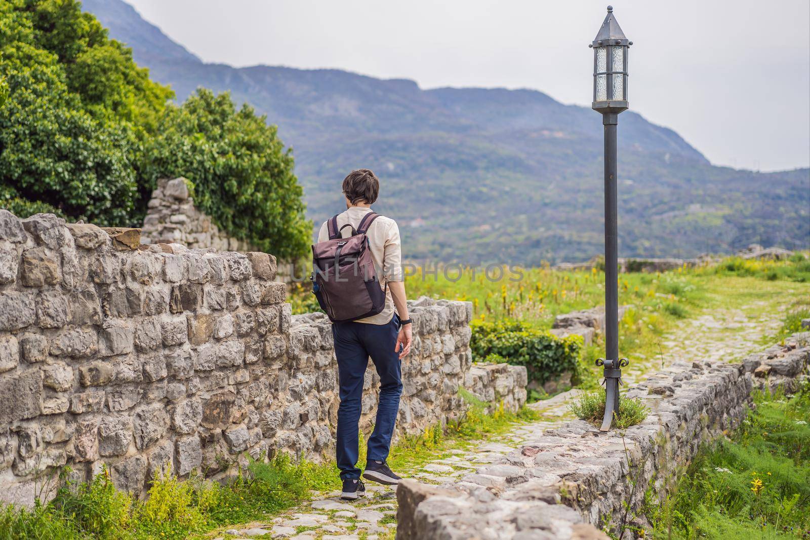 Man tourist walks through the old town of Bar in Montenegro. Happy tourist walks in the mountains. Suburbs of the city of Bar, Montenegro, Balkans. Beautiful nature and landscape.