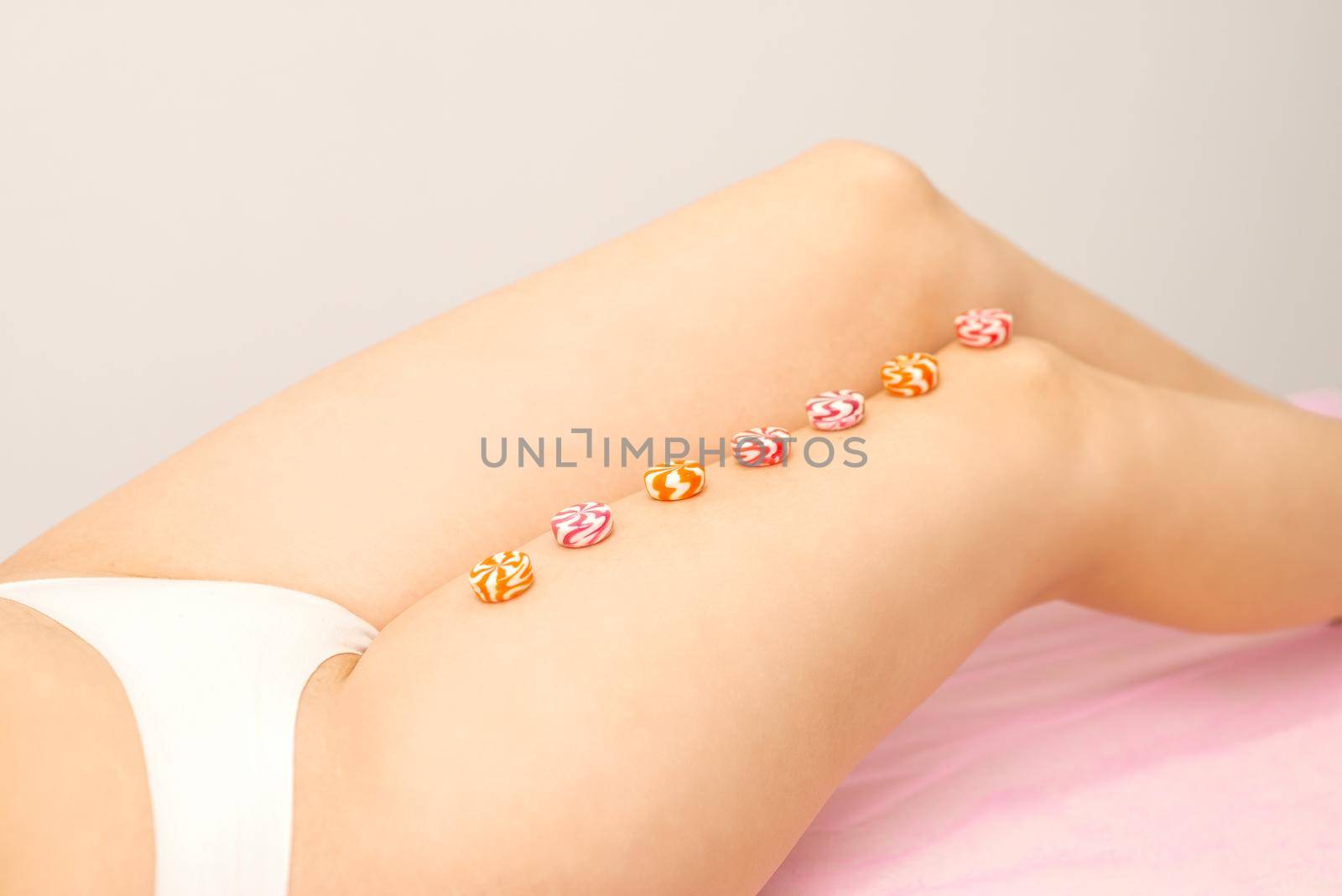 Depilation, waxing concept. Round candies lying down in a row on the female leg, close up. by okskukuruza