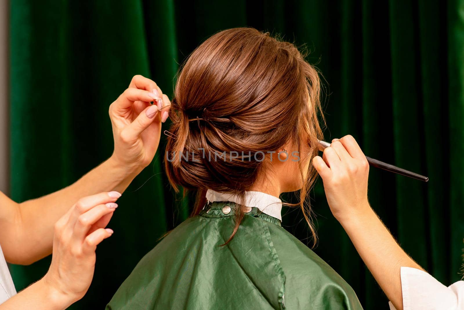 Makeup artist and hairdresser prepare the bride making hairstyle and makeup in a beauty salon. by okskukuruza