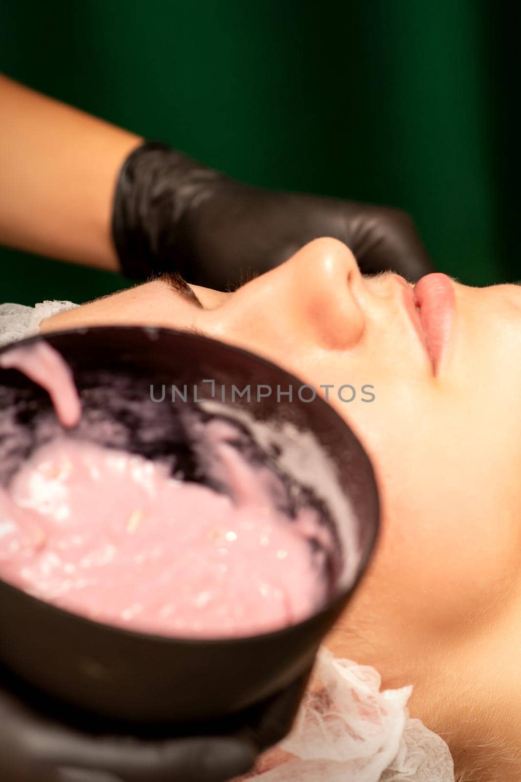 Beautiful young caucasian woman receiving an alginic mask to the face in beauty salon. Facial skin treatment