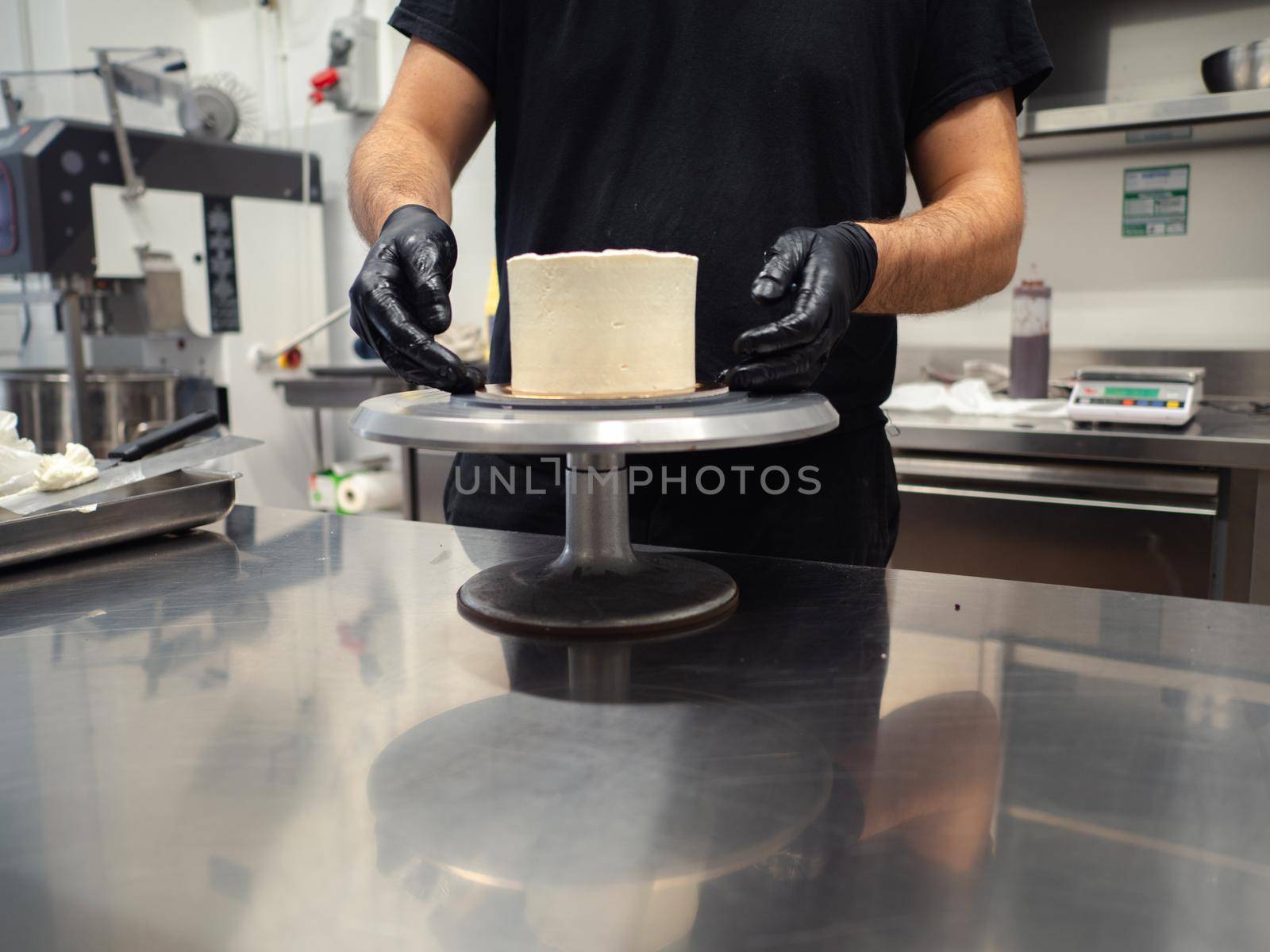 Decorator using spatula and scraper to smooth buttercream on a frosted cake