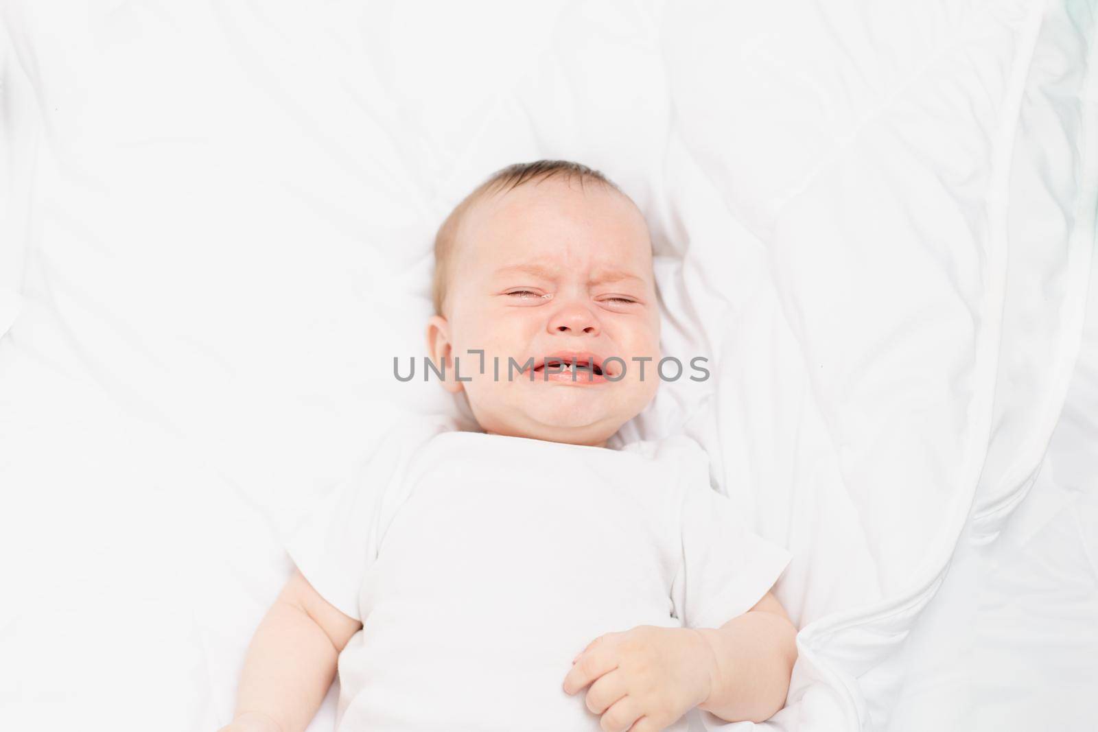 The baby is crying in his crib . The baby 's teeth are teething . Colic in babies . Hungry baby . Baby on a white background
