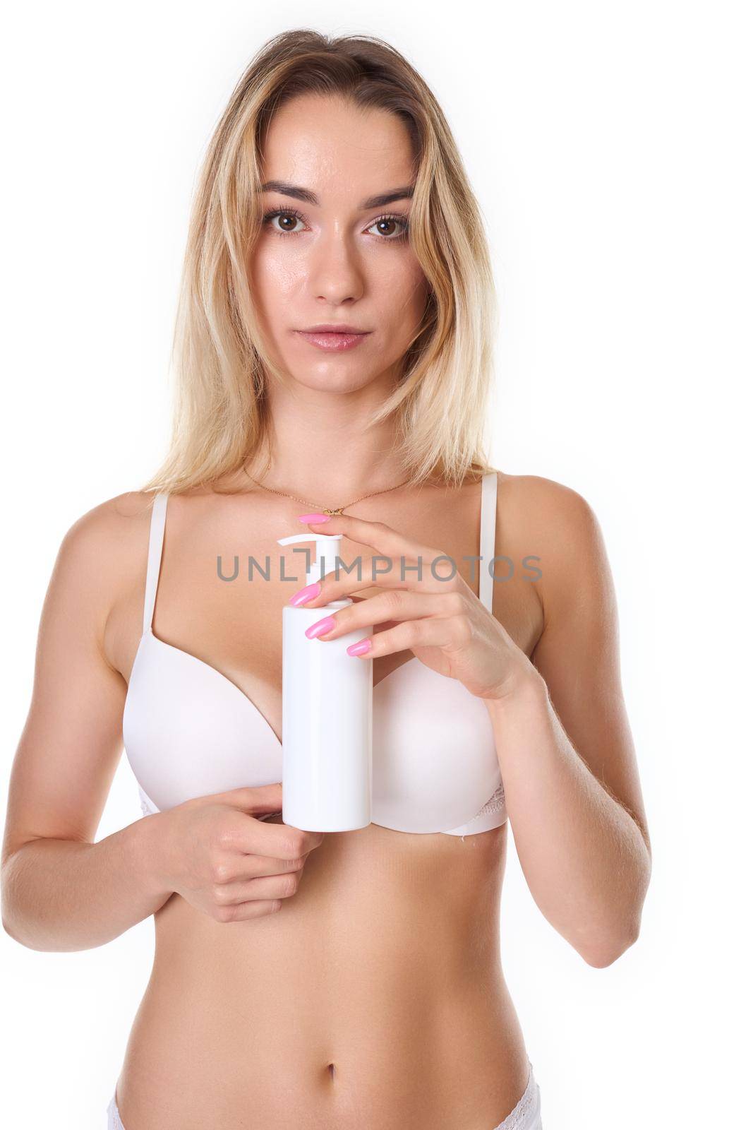 a woman with blonde hair poses in white lingerie and uses a body lotion. Photo taken in the studio. photo on a white background