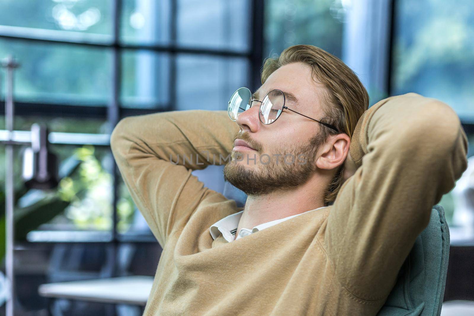 Man resting at home, young guy with closed eyes in glasses, hands behind head by voronaman