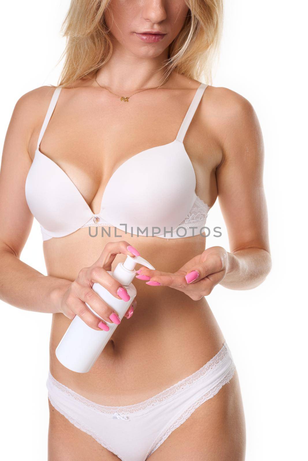 a woman with blonde hair poses in white lingerie and uses a body lotion. Photo taken in the studio. photo on a white background