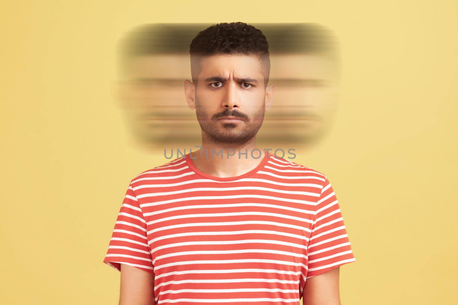 Triple exposure creative portrait of serious handsome bearded man in red t-shirt looking at camera with angry face. Mental health concept. Indoor studio shot isolated on yellow background.
