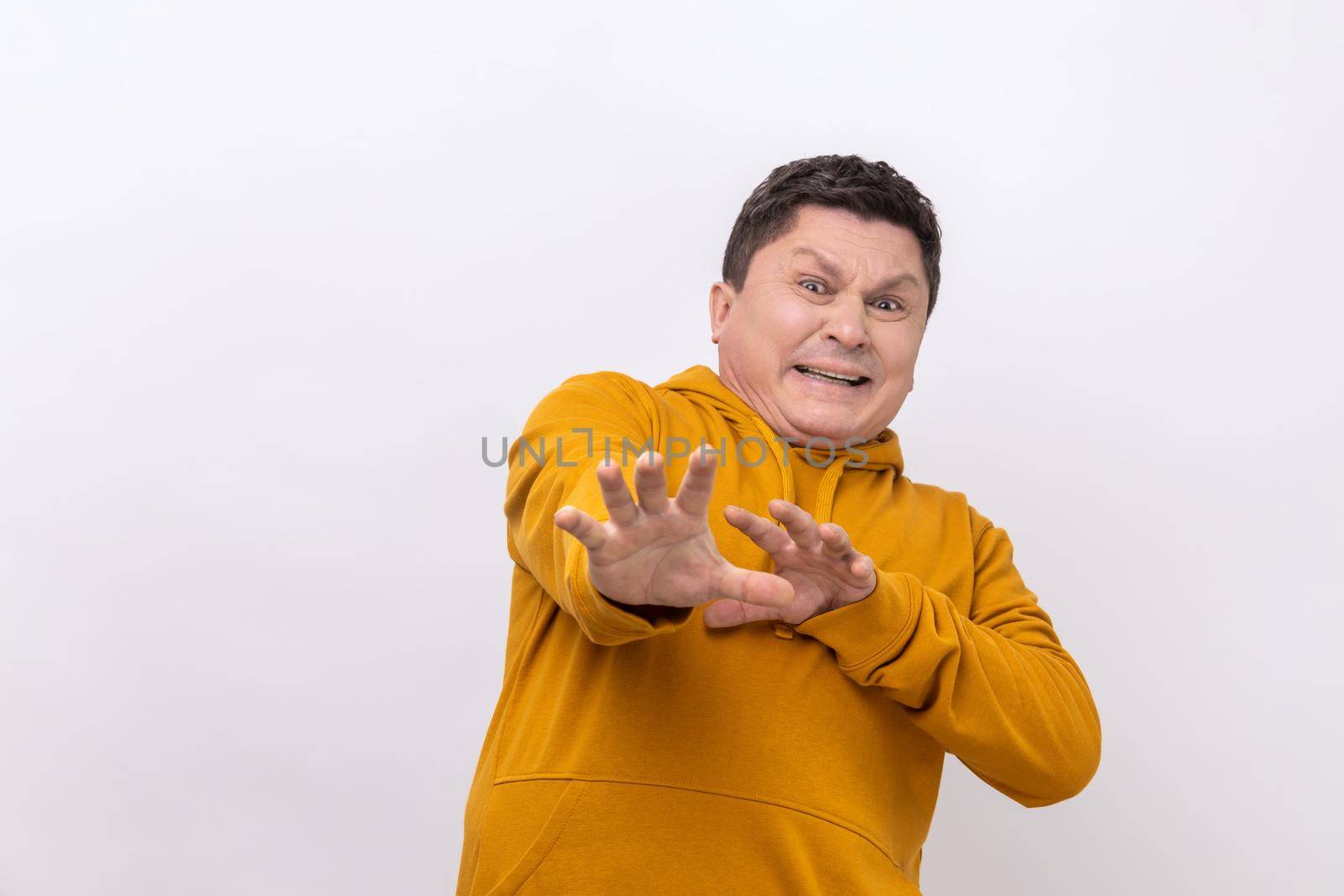 Stop. Portrait of scared man standing with afraid or worry face, looking at camera and blocking with his hands, wearing urban style hoodie. Indoor studio shot isolated on white background.