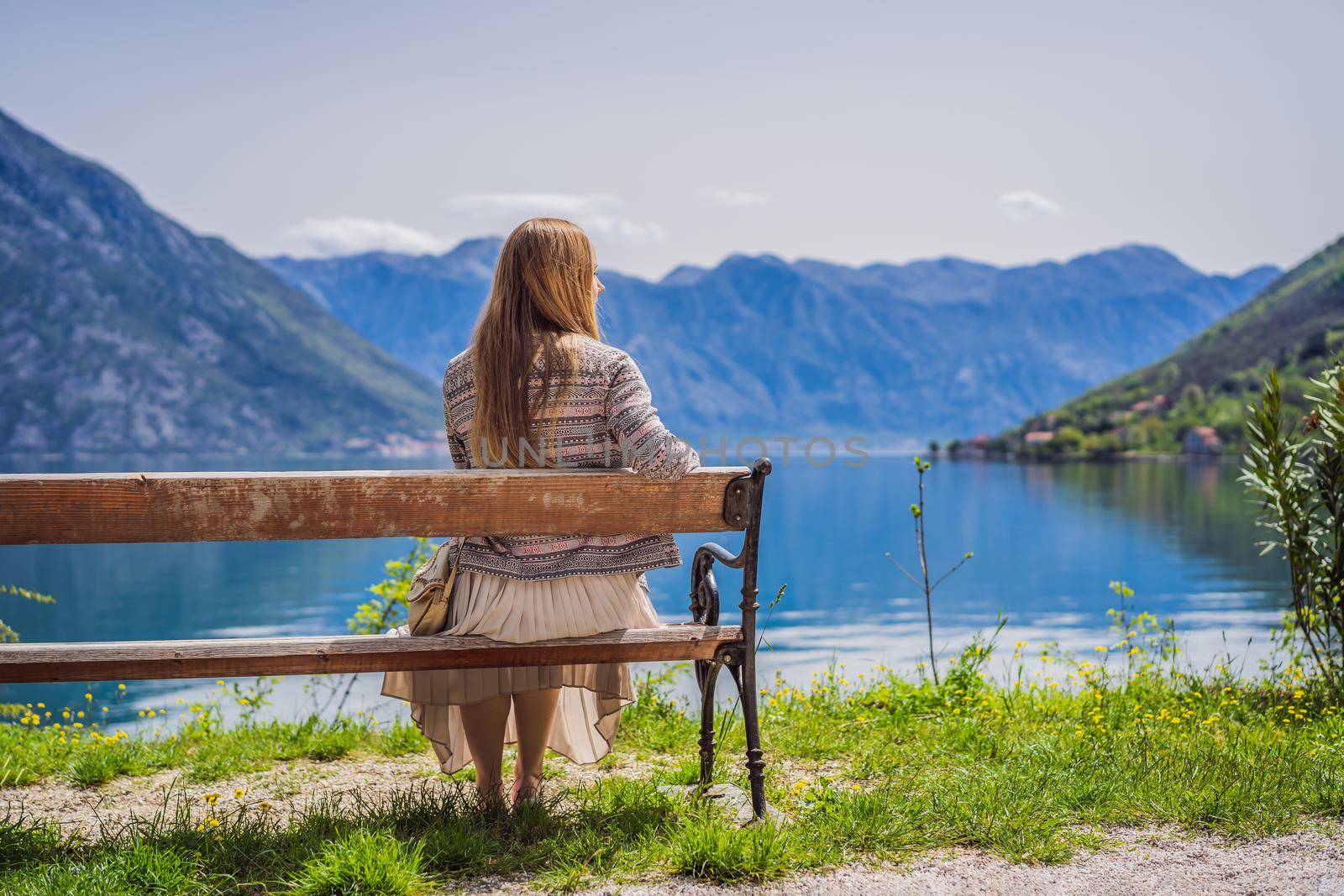 A woman sits on a bench and admires the view of the Bay of Kotor. Montenegro.