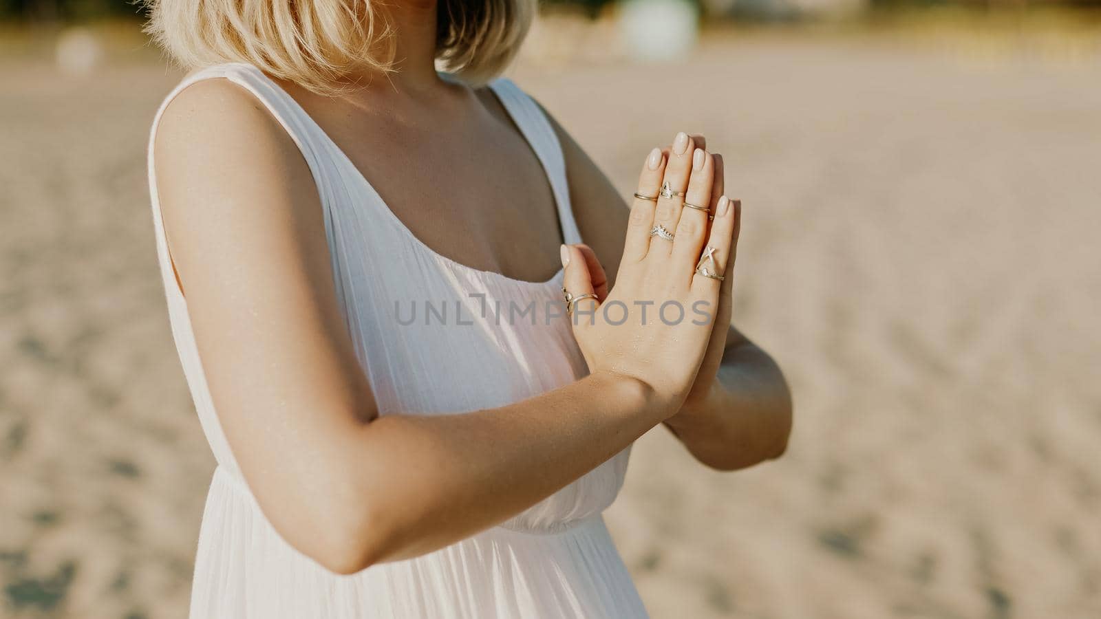 Praying meditating woman, reading mantras, directs thoughts, requests or gratitude to universe. Beach, morning near sea. Spirituality, religion, God concept. by kristina_kokhanova