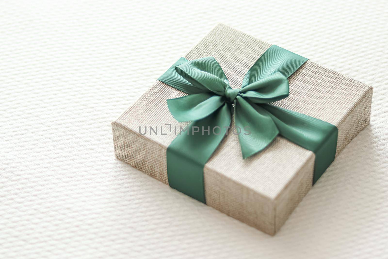 Holiday present and luxury online shopping delivery, wrapped linen gift box with green ribbon on bed in bedroom, chic countryside style, close-up