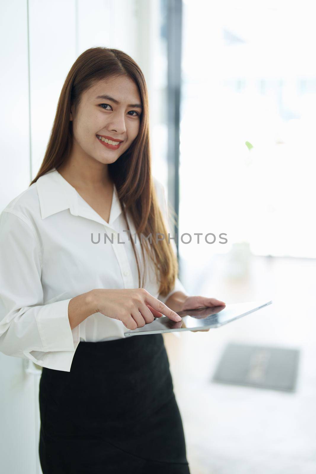 Portrait of a female business owner showing a happy smiling face as he has successfully invested his business using computers and financial budget documents at work.