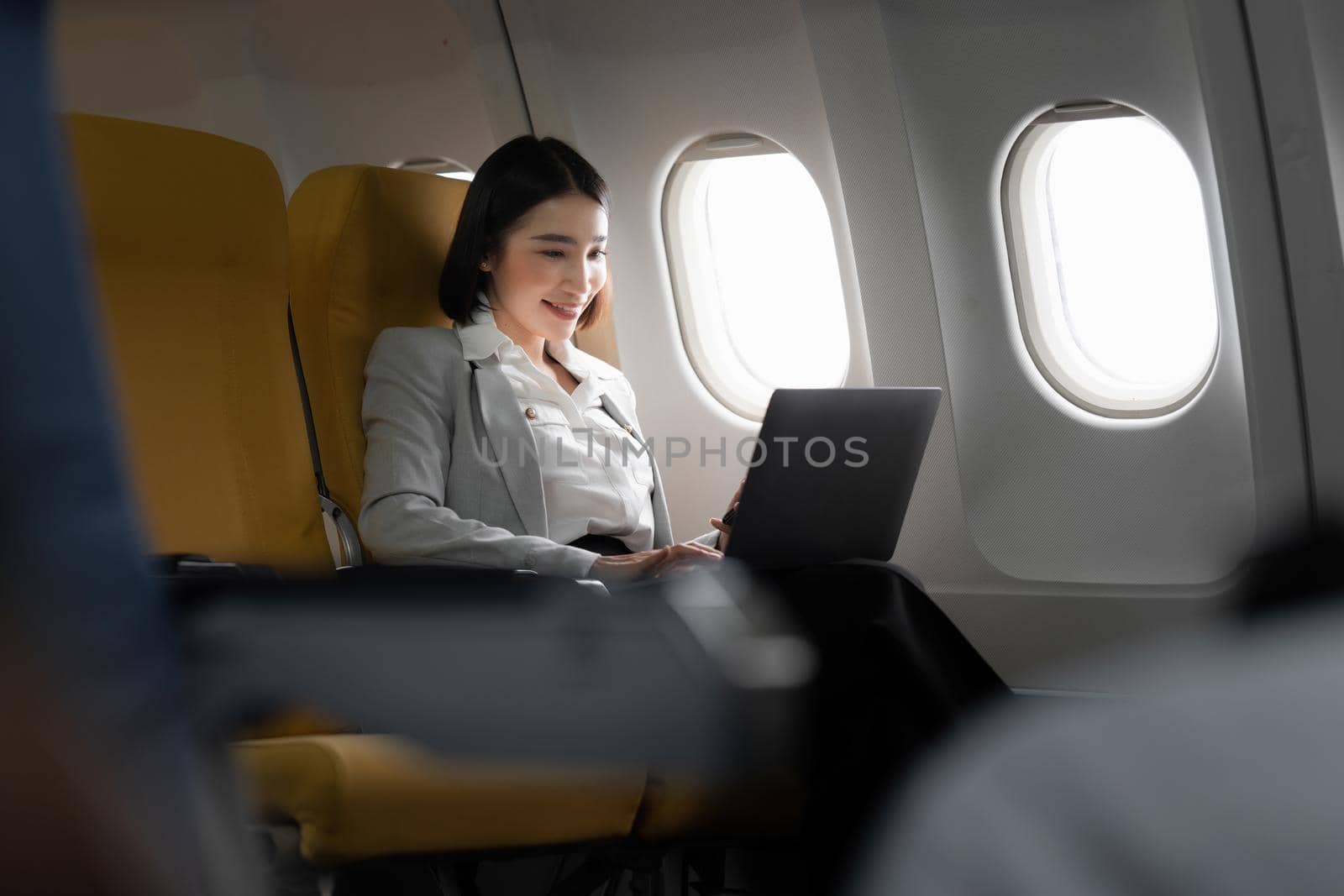 Fund investment woman sitting in airplane and checking the project before meeting to client. working and travel concept.