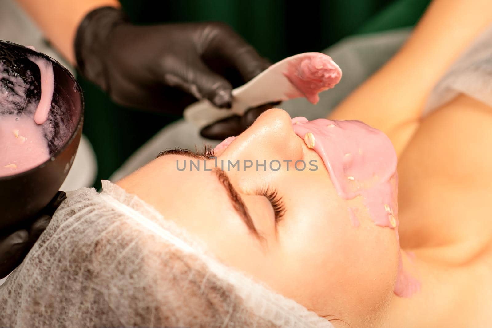 Beautiful young caucasian woman receiving an alginic mask to the face in beauty salon. Facial skin treatment