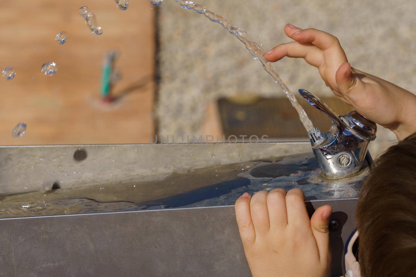 close-up of a child's hands playing with the water jet of a fountain