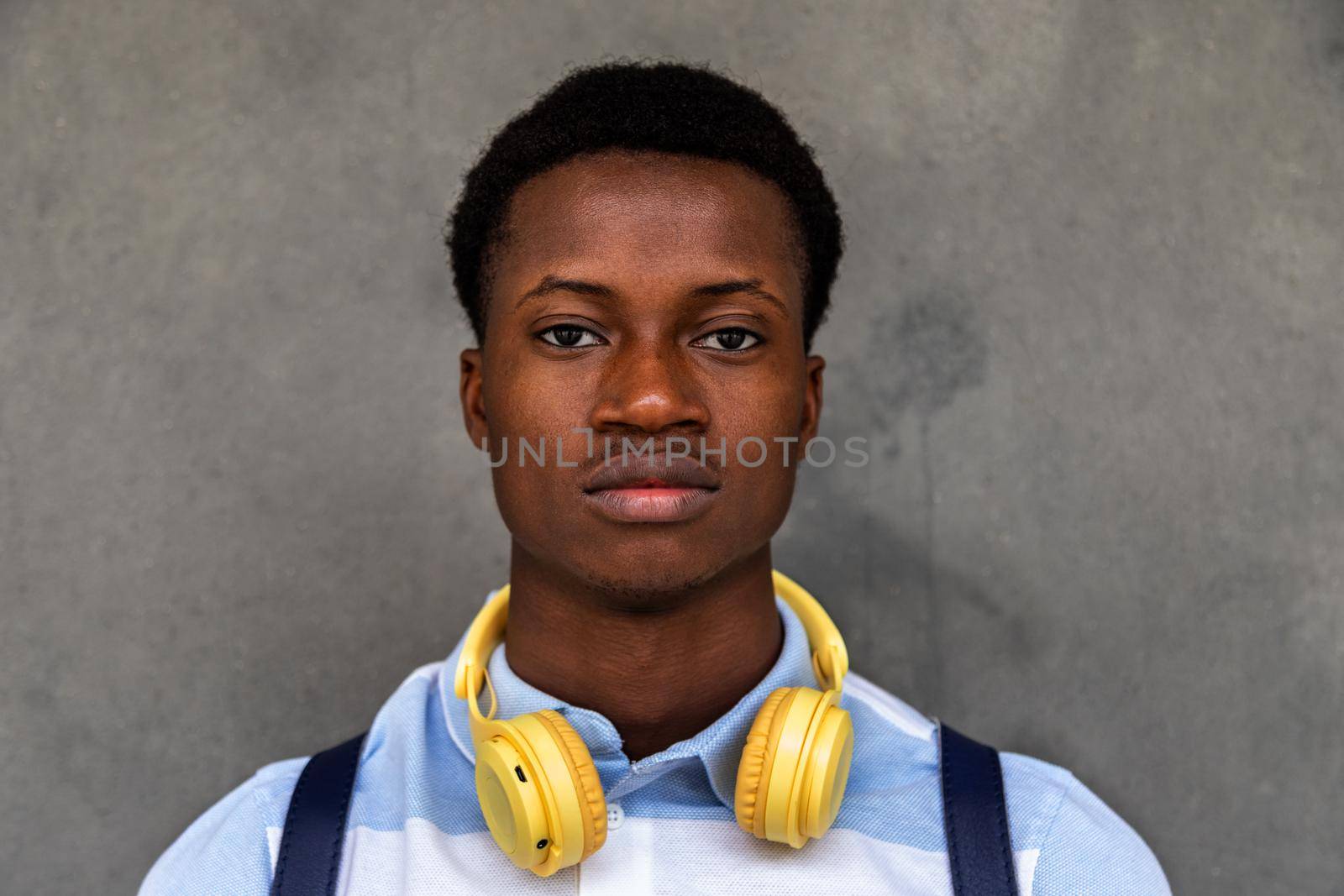 Teen African American male high school student looking at camera with serious expression. Back to school concept.