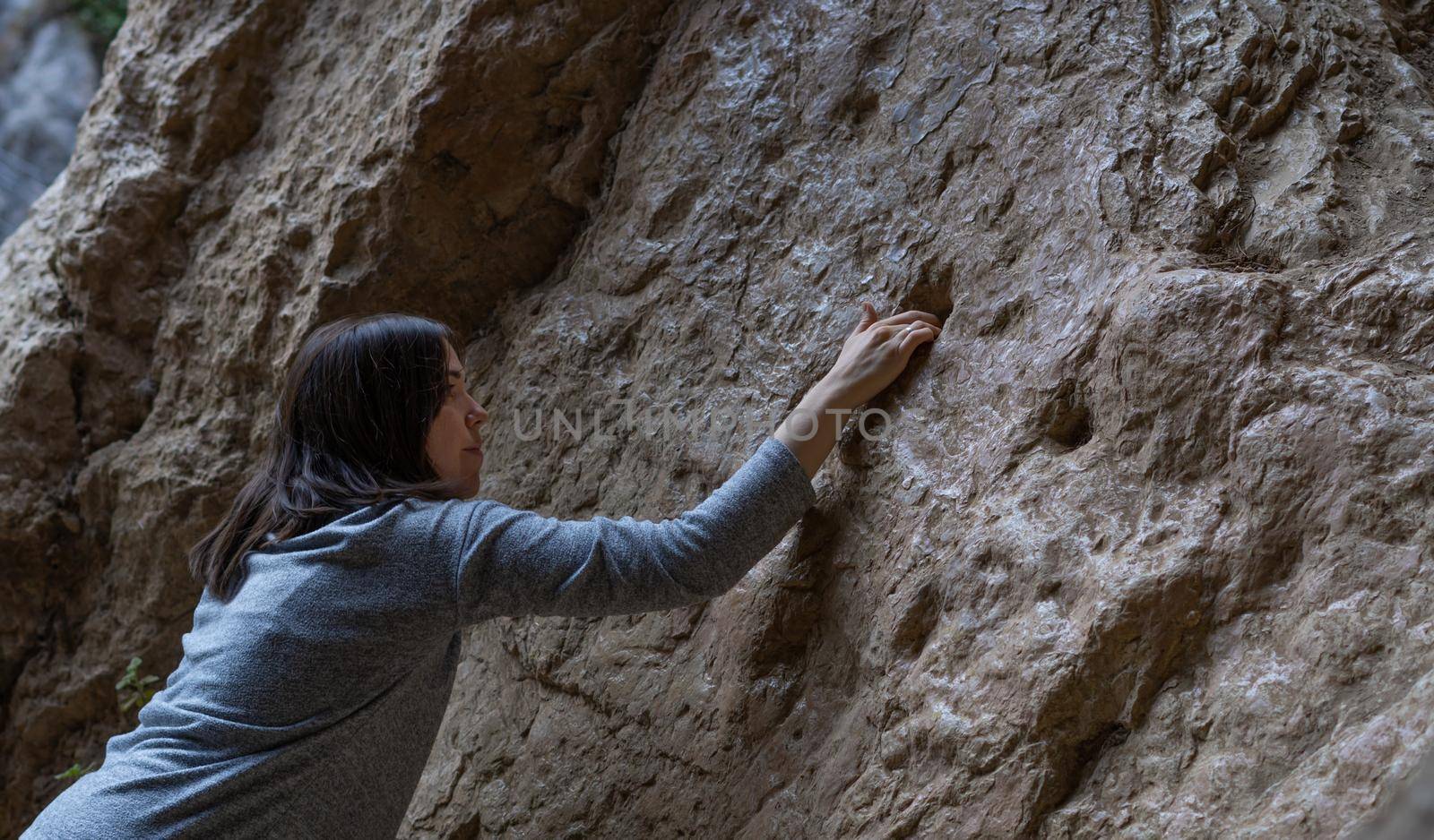 young girl learning rock climbing in high mountain with blue sweater, black tights and boots.