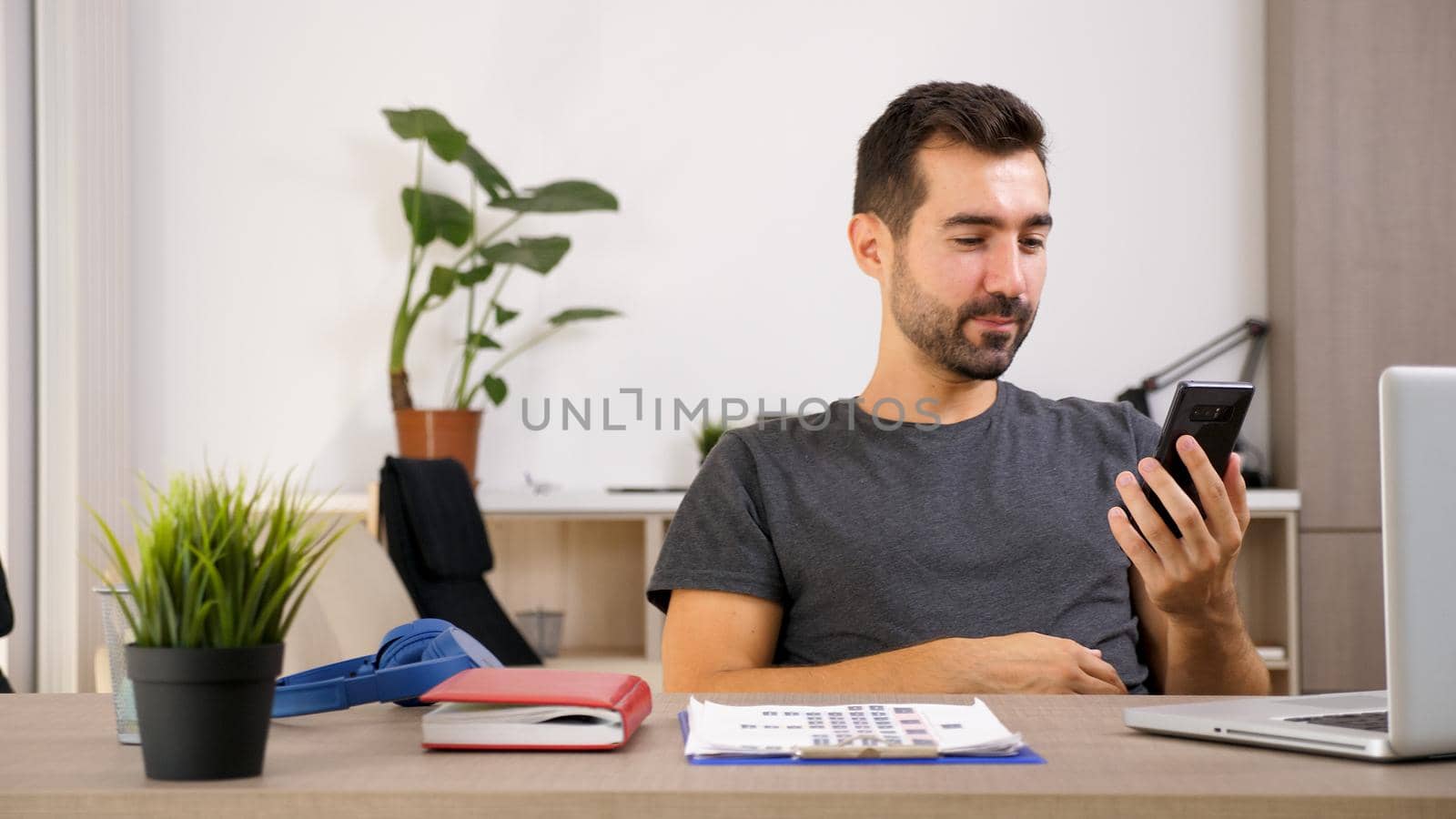 Young man talking on the phone while he's at the office by DCStudio