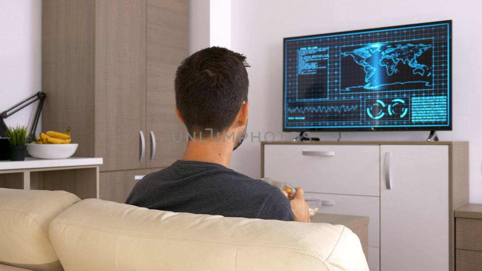 Attractive young man sitting on his couch and playing video games. Relaxing being home.