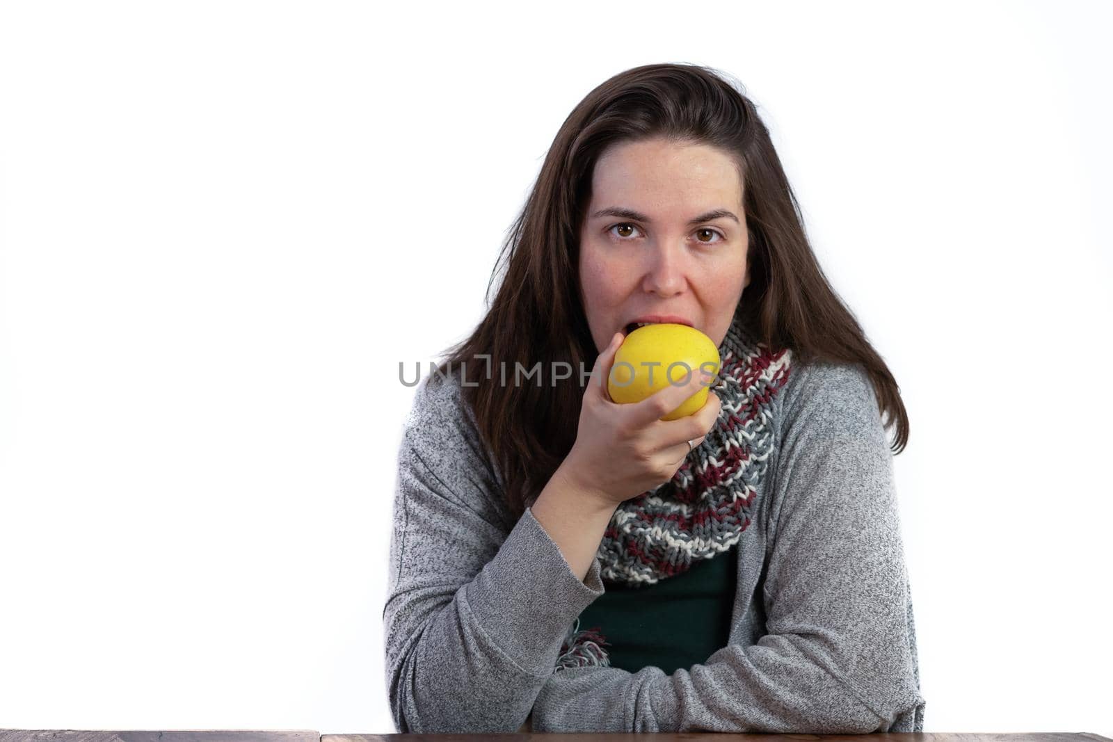young brunette girl eating an apple on a white background with copy space
