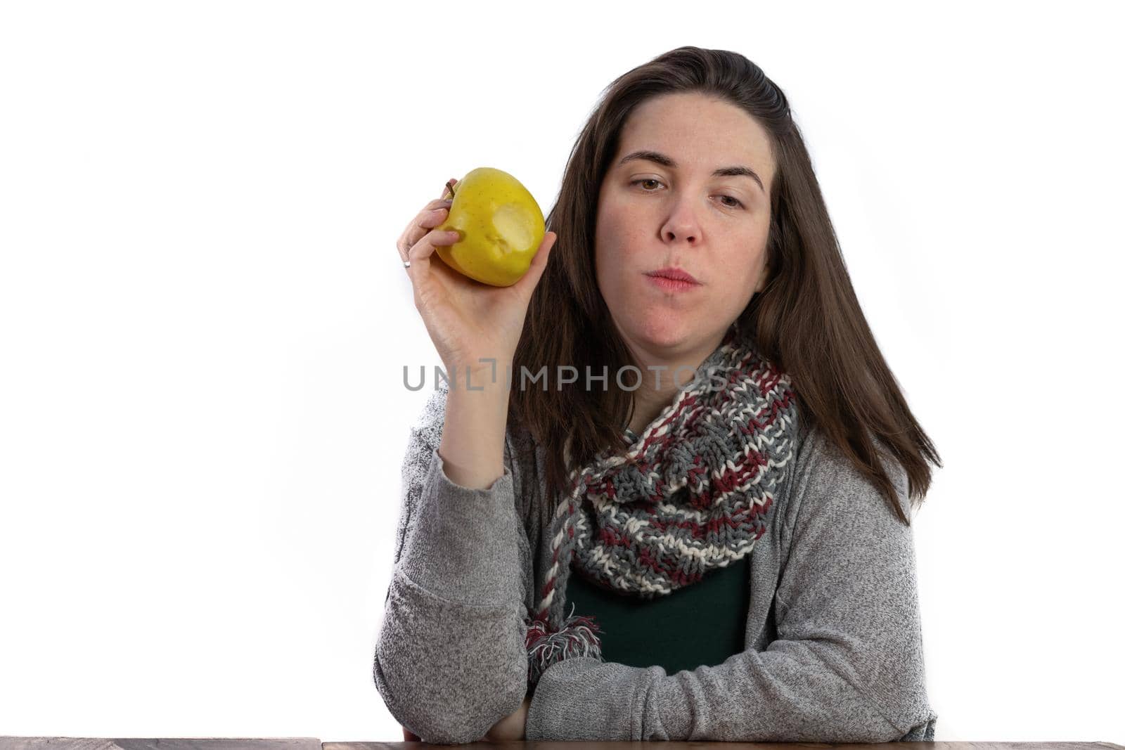 young brunette girl eating an apple on a white background with copy space