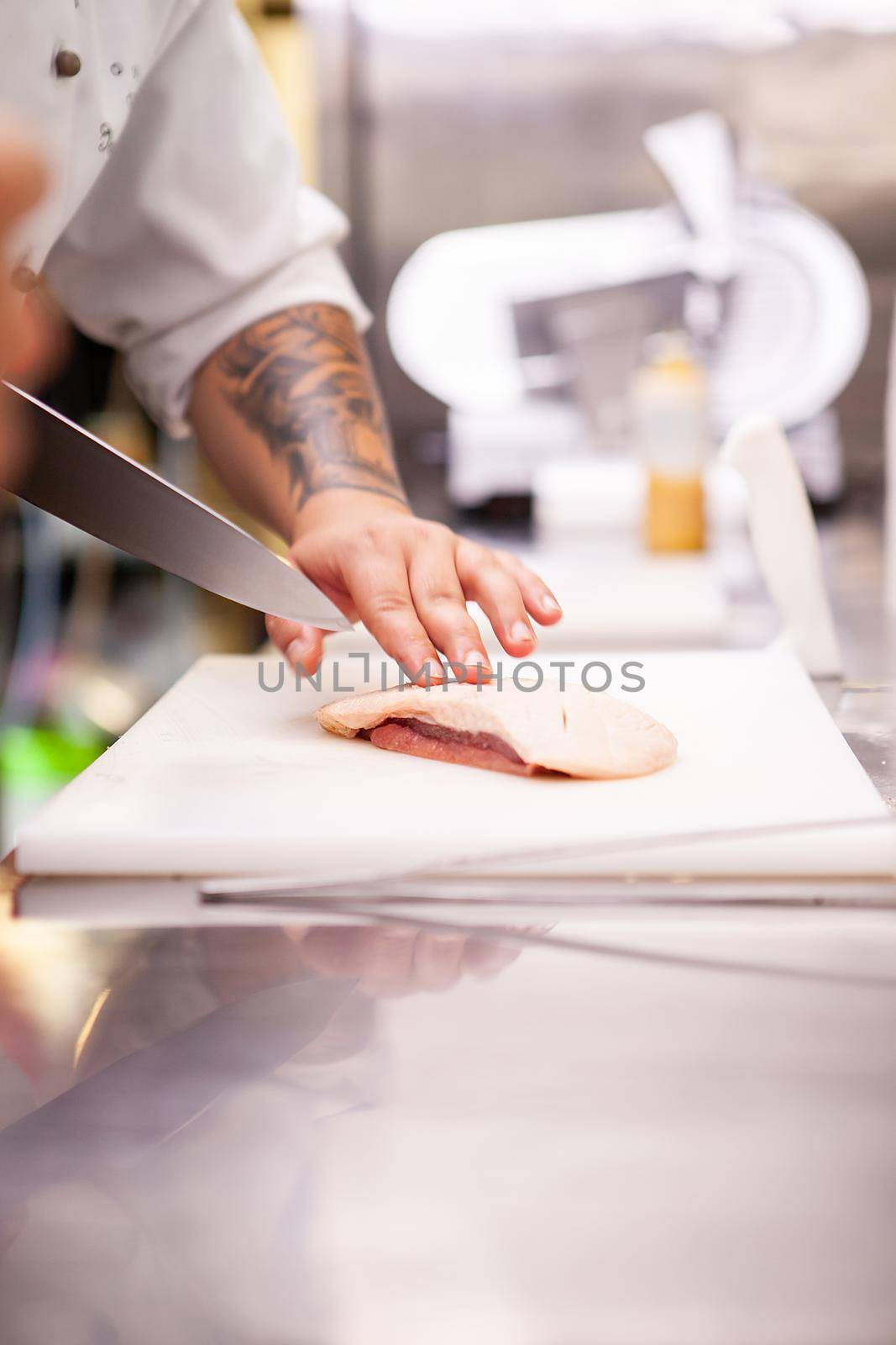 Chef slicing duck breast in kitchen restaurant. Meat preparation