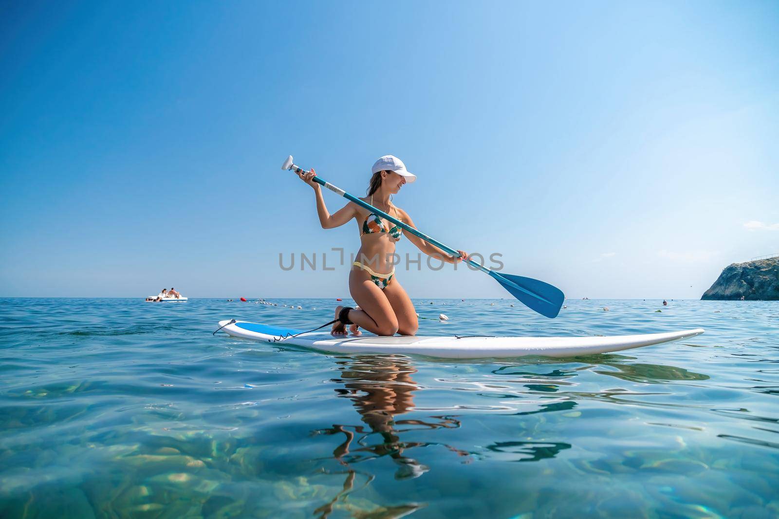 SUP Stand up paddle board. Young woman sailing on beautiful calm sea with crystal clear water. The concept of an summer holidays vacation travel, relax, active and healthy life in harmony with nature. by panophotograph