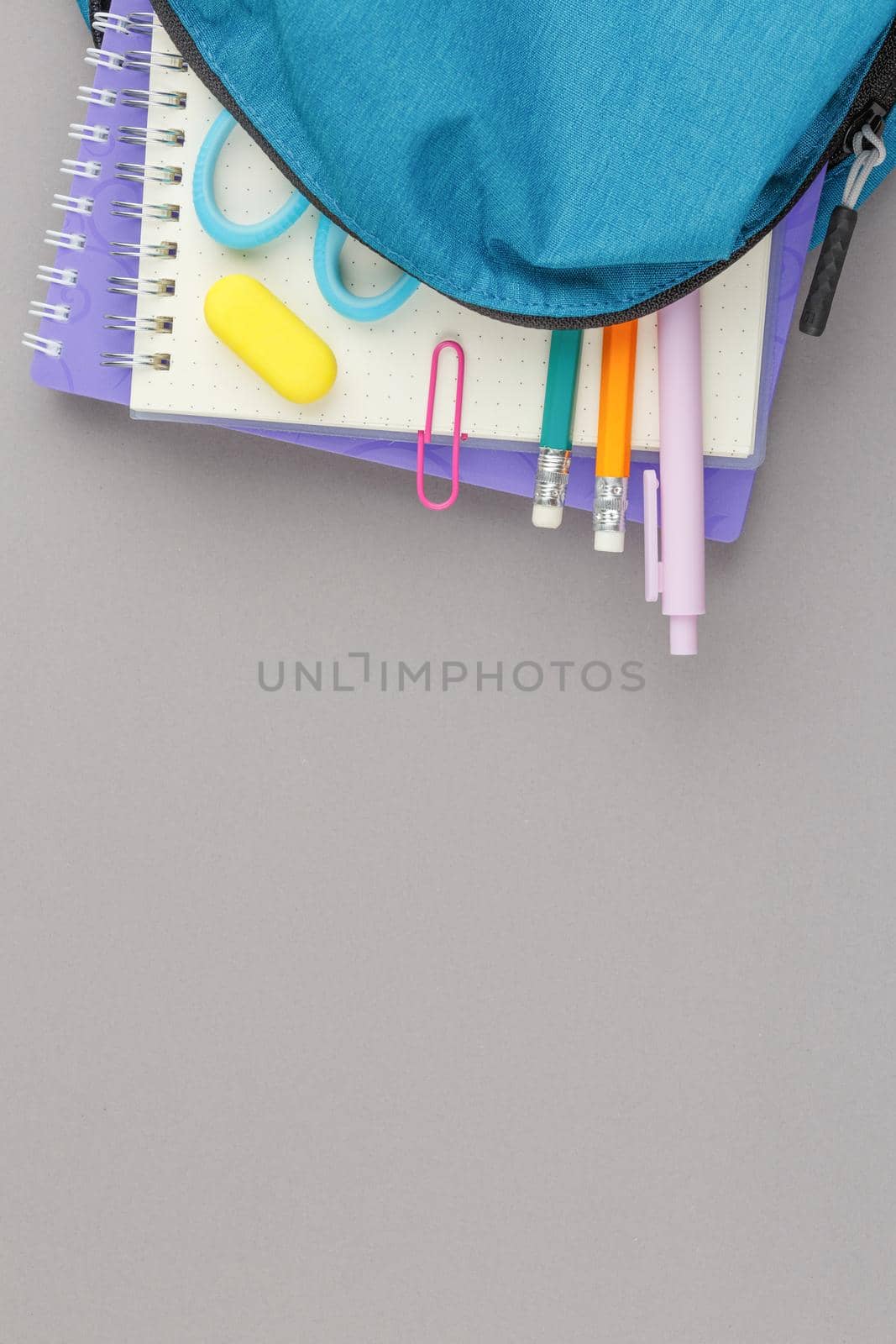 Back to school concept. School backpack with educational supplies on a grey background. Top view. Flat lay student desk.
