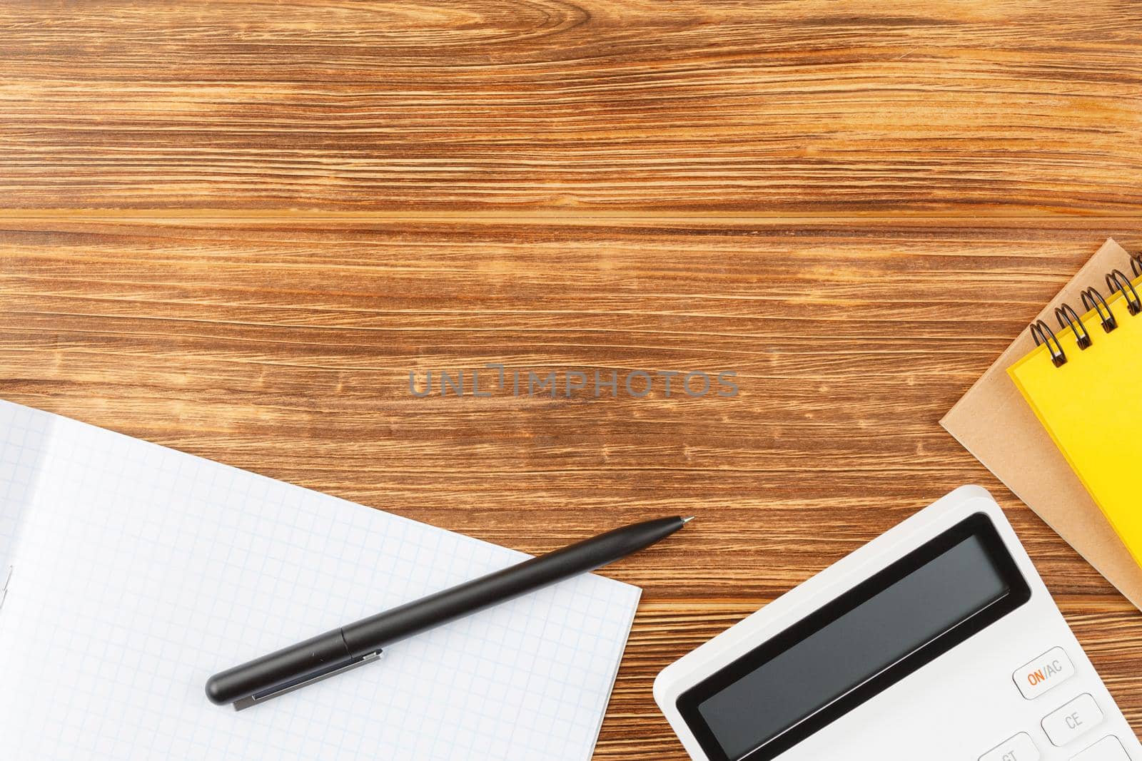 Open notebook with pen and calculator on wooden background. Study desk. Flat lay. Back to school concept. Top view.