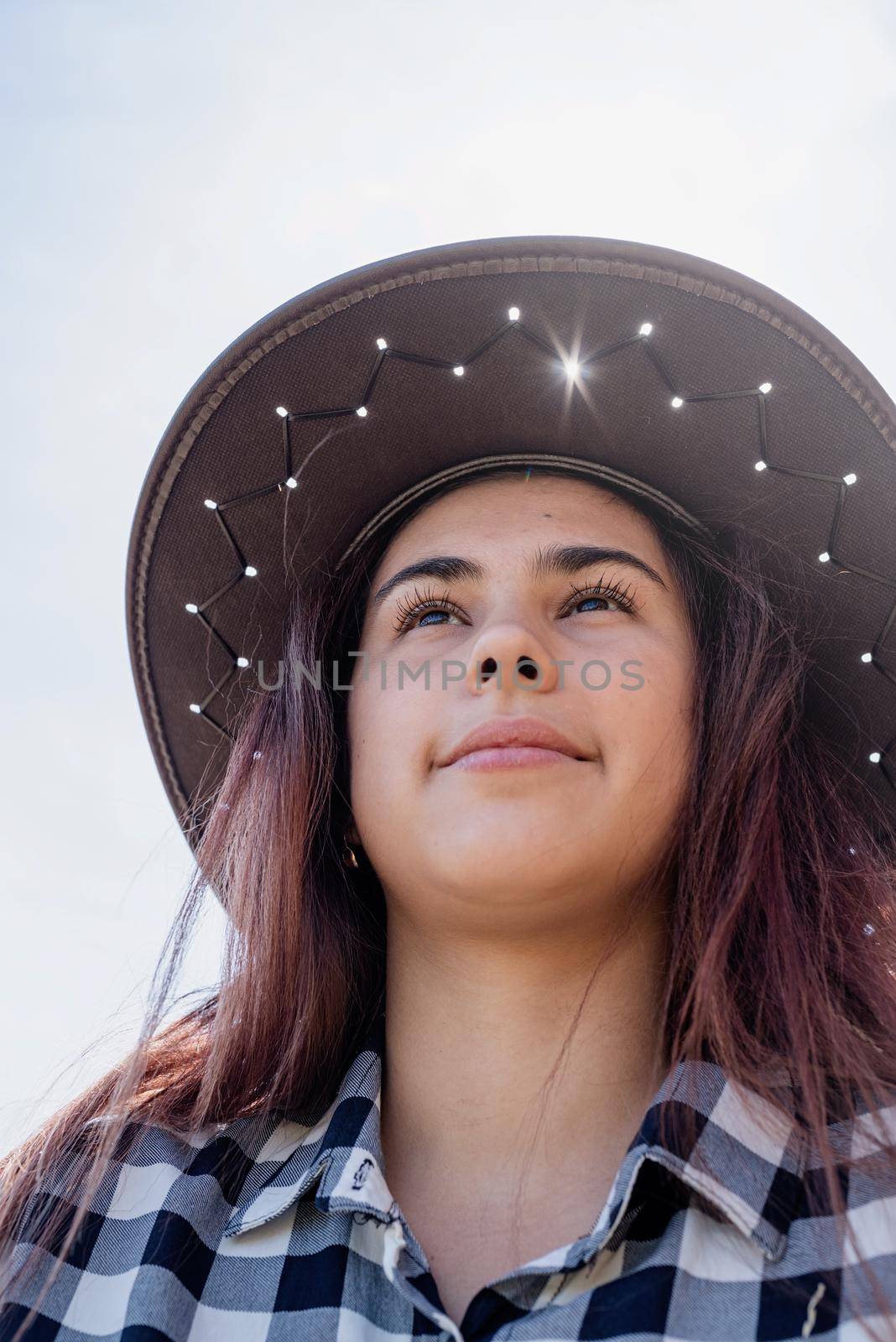 beautiful woman in plaid shirt and cowboy hat resting on haystack by Desperada