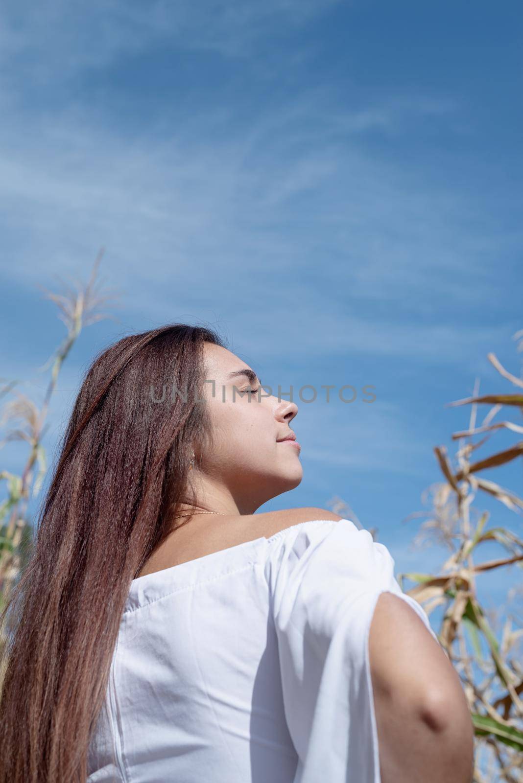 Cheerful caucasian woman in white dress in the corn crop, sky background by Desperada