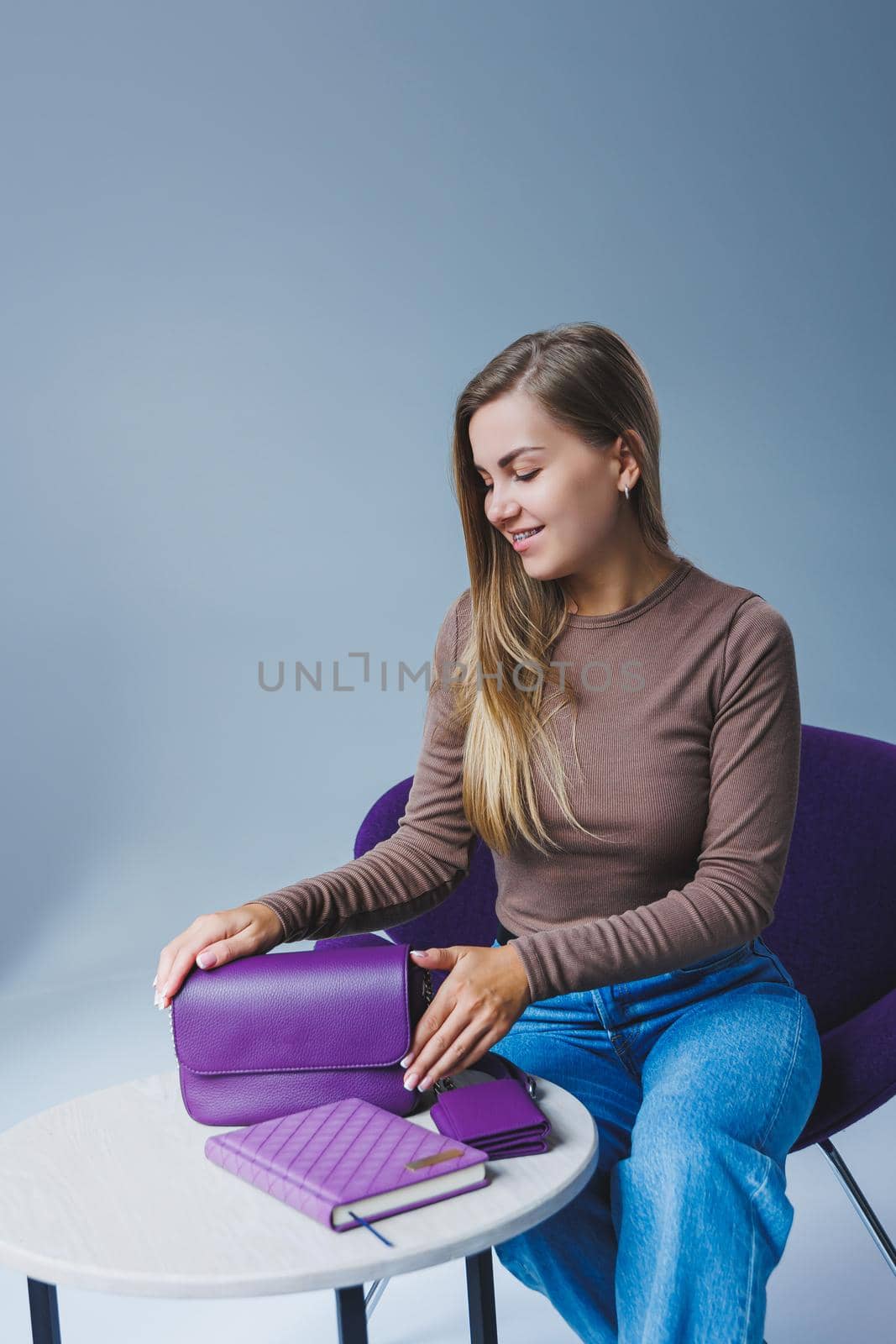 A purple leather bag in a girl's hand. Woman with luxury bag.