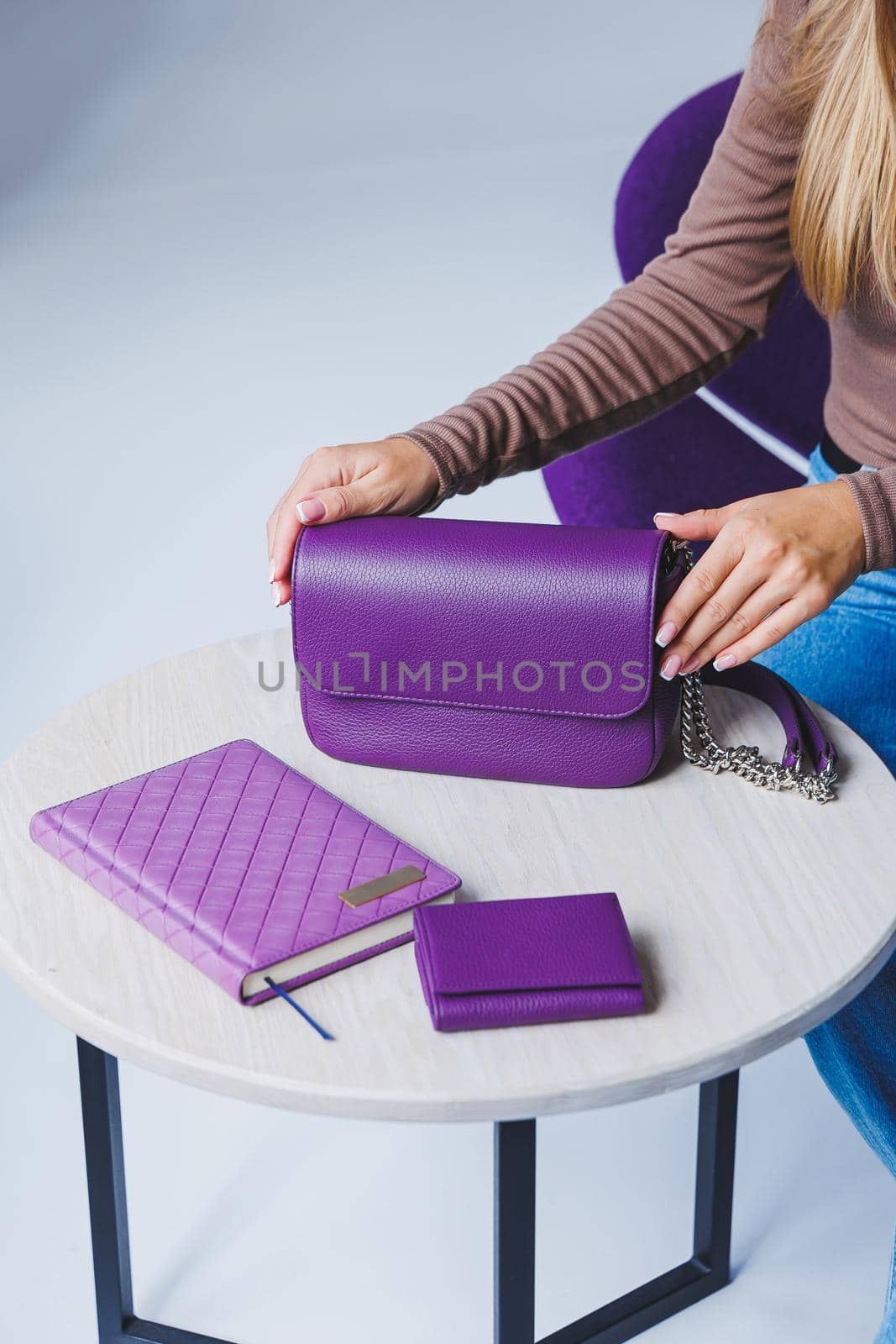 A purple leather bag in a girl's hand. Woman with luxury bag.